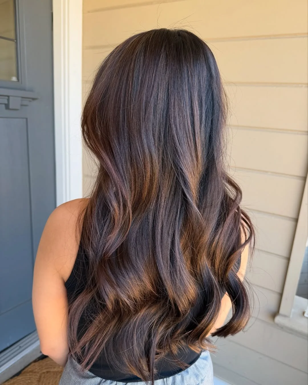 Back view of a woman with long, wavy hair that transitions from dark brown to caramel highlights. Hairstyle done by Caitlin Duffy Hairstylist at Bolt Collective Hair Salon in Pleasanton, CA.