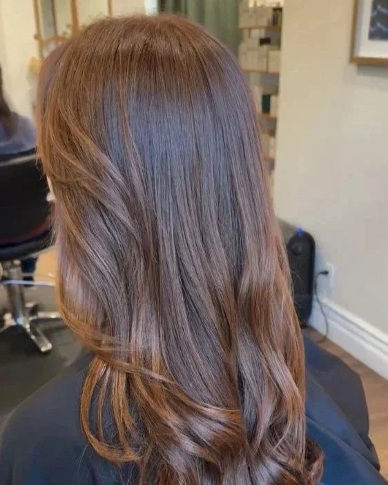 Back view of a woman with long, wavy, light brown hair in a salon. Hairstyle done by Caitlin Duffy Hairstylist at Bolt Collective Hair Salon in Pleasanton, CA.