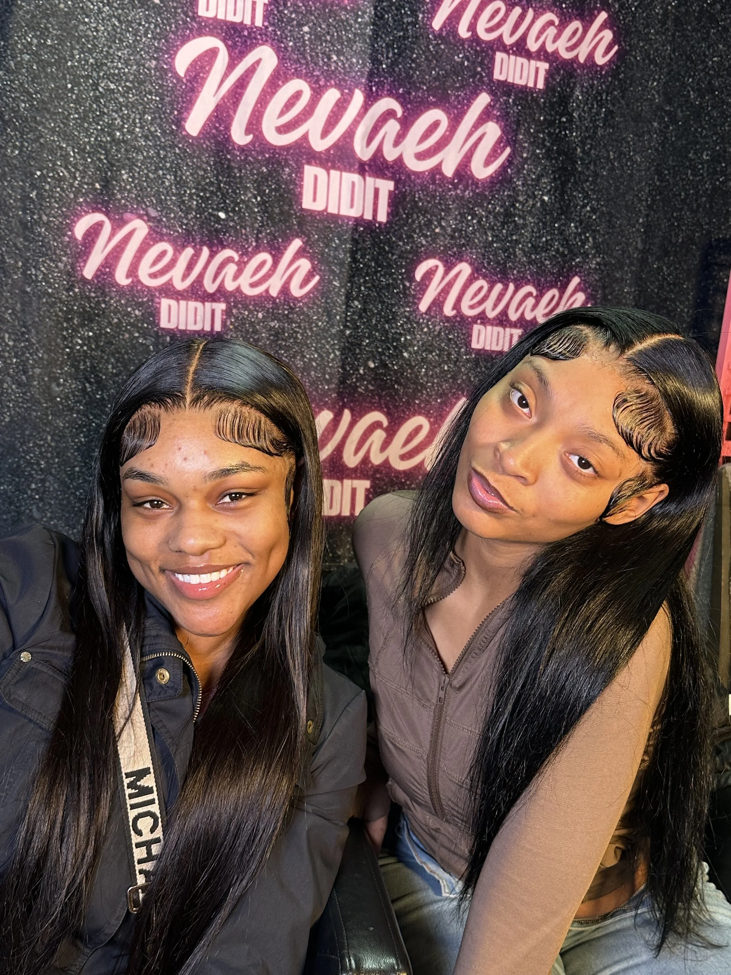 Two young women with long black hair and stylized baby hair waves on their foreheads taking a selfie in front of a black glittery backdrop with pink neon-style text that says 'Newah Did It' repeated multiple times.