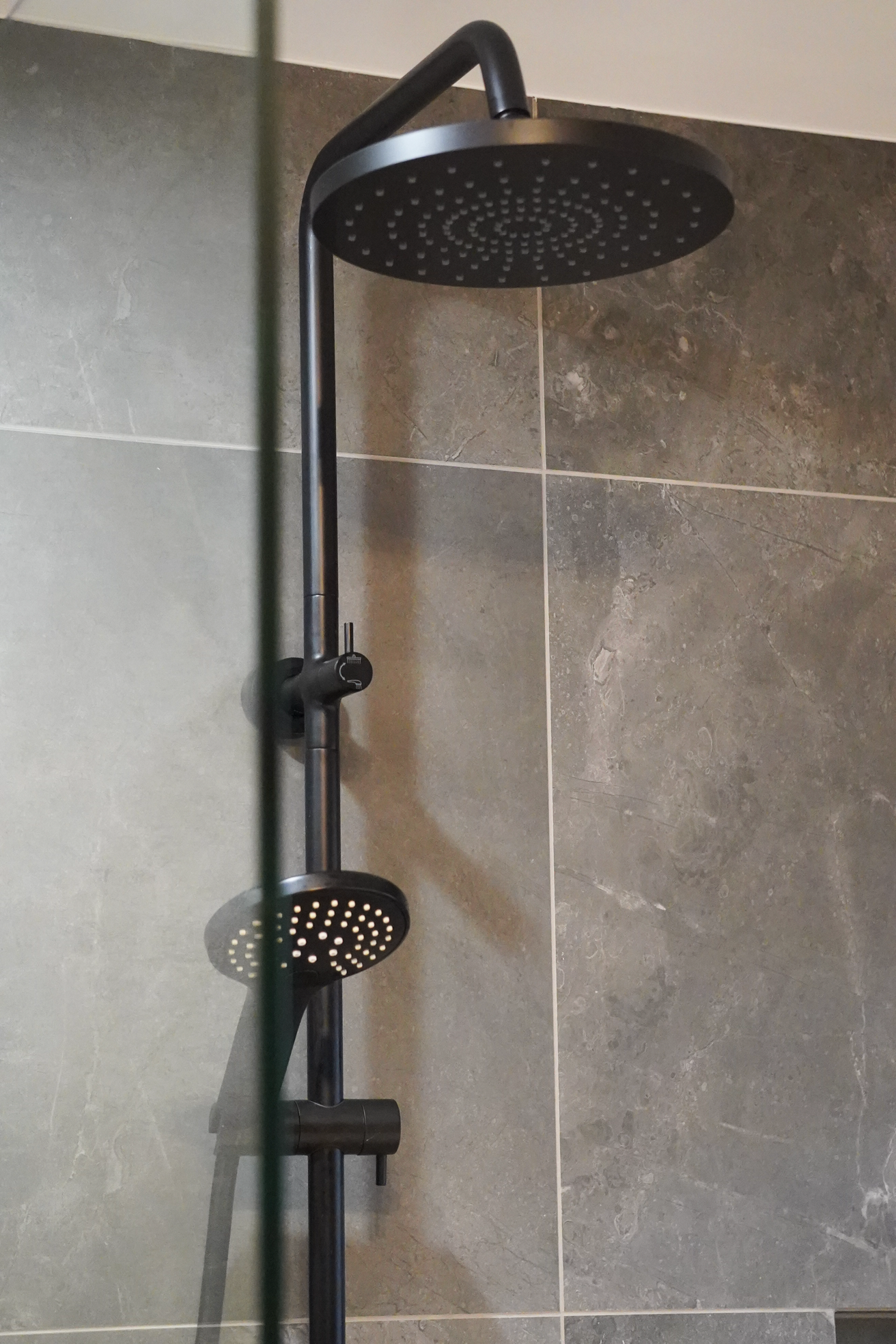 Black showerhead mounted on a tiled bathroom wall.