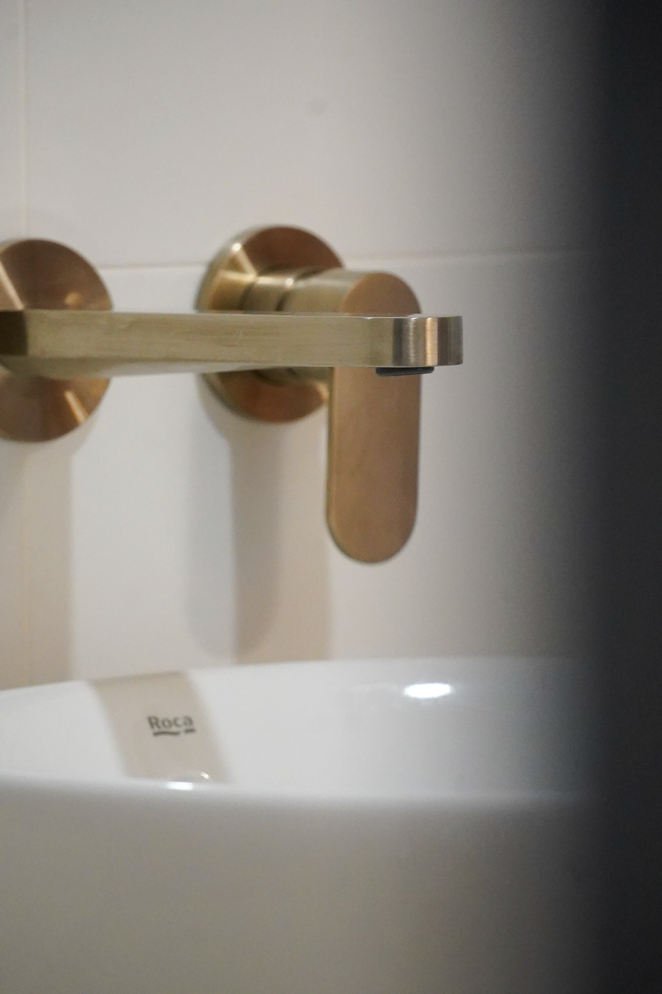 Close-up of a modern, metallic door handle on a white door, with a label that reads 'Roca' visible beneath the handle.