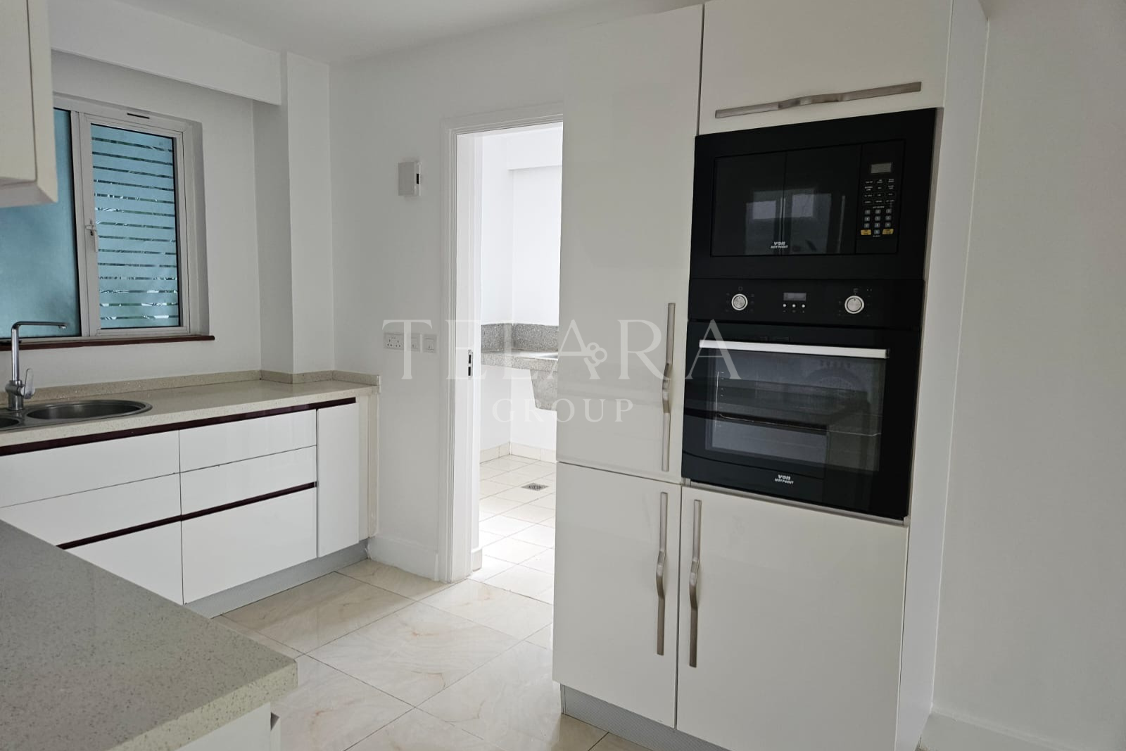 Modern kitchen with white cabinets, a granite countertop, a window, and built-in microwave and oven.