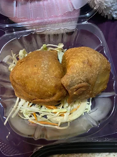 Two fried chicken drumsticks on a bed of coleslaw in a plastic container.
