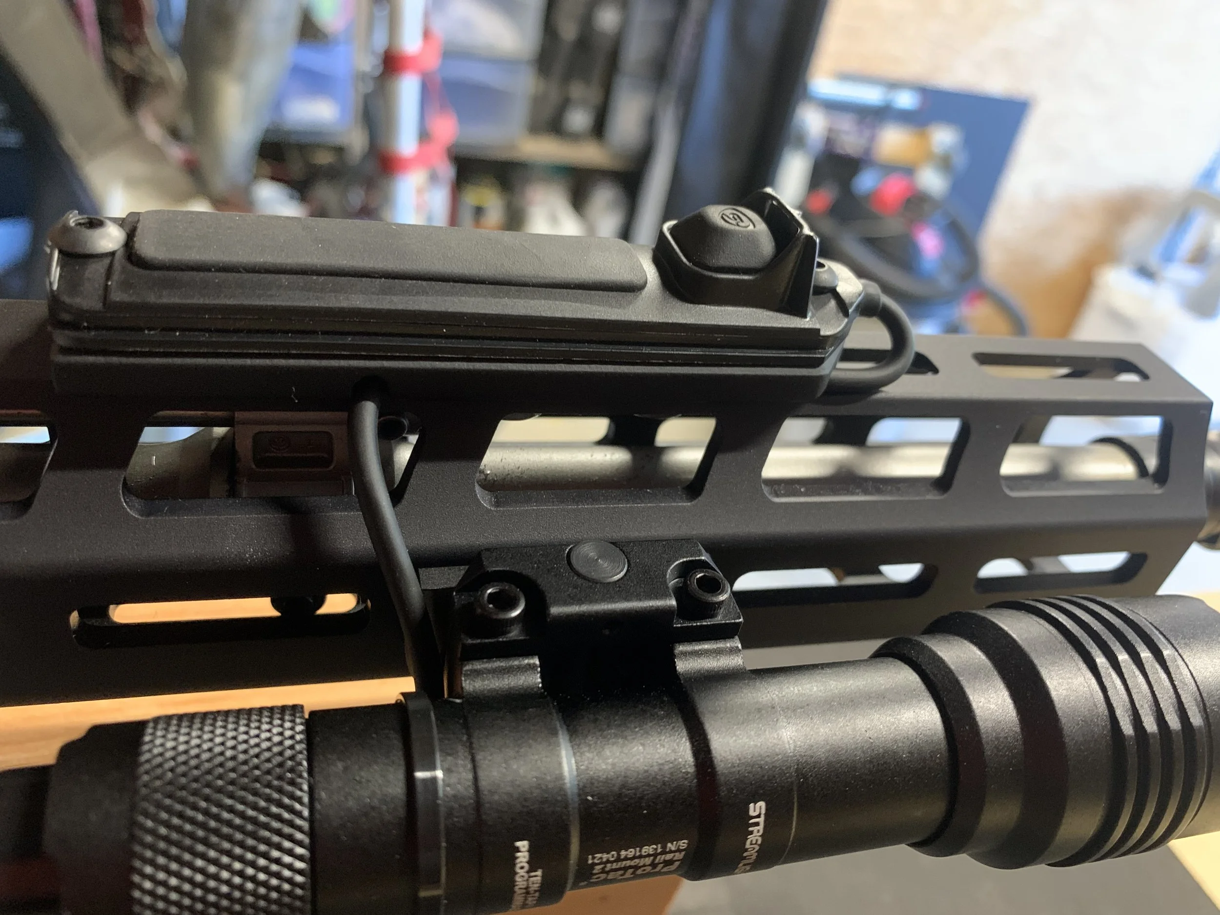 Close-up of a tactical firearm with mounted accessory, featuring a flashlight, mounted on a handguard.