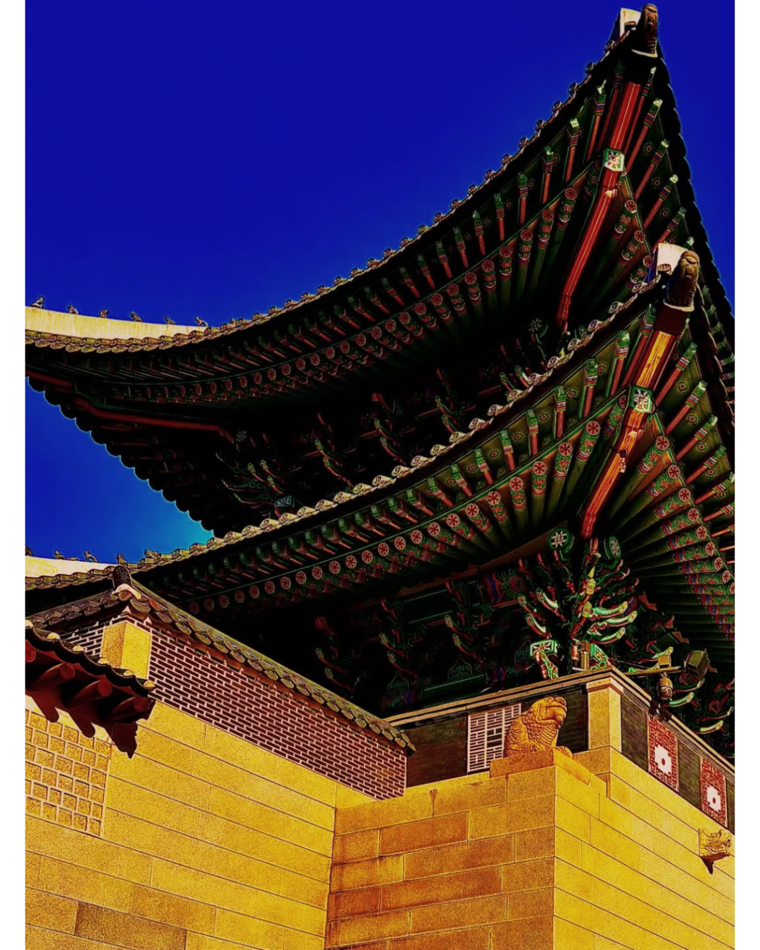 Close-up of a traditional Asian temple roof with intricate details, colorful patterns, and curved eaves against a clear blue sky.