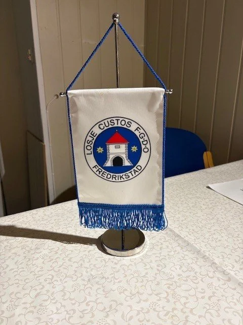 Vimpler med emblem for Losje Custos F.G.10 Fredrikstad på bord.