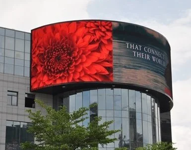 Stor digital skjerm som viser en stor rød blomst og tekst på en glassbygning