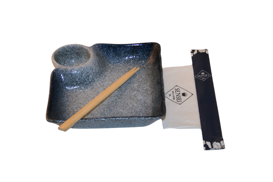 Tallerken, nesje, spisepinner, sugerør og servietter på et spisebord.