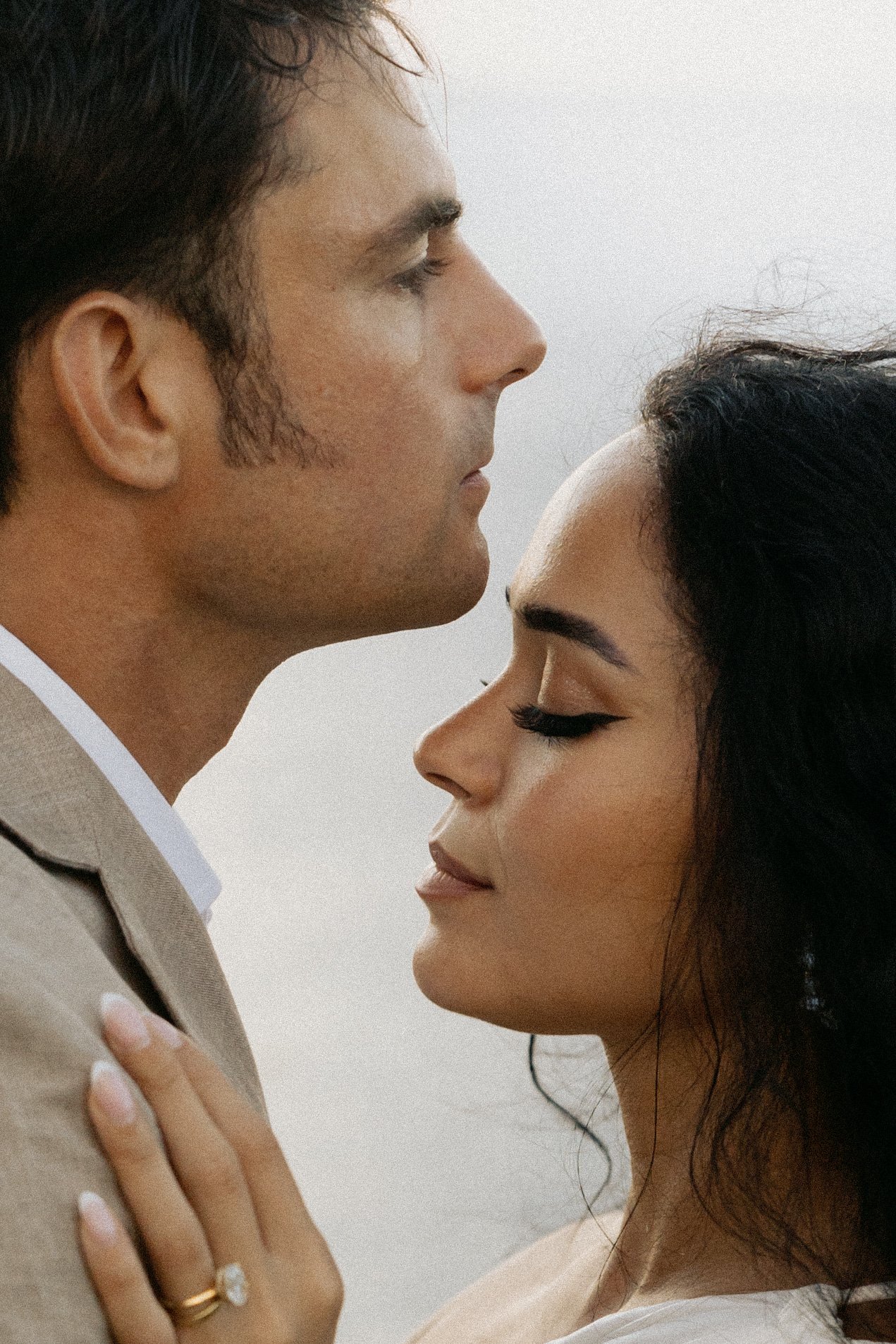 A man and woman with eyes closed, forehead to forehead, in a tender embrace, capturing an intimate moment.