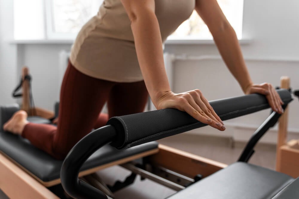 Une personne effectuant un exercice sur un appareil de Pilates, en appui sur ses mains et genoux