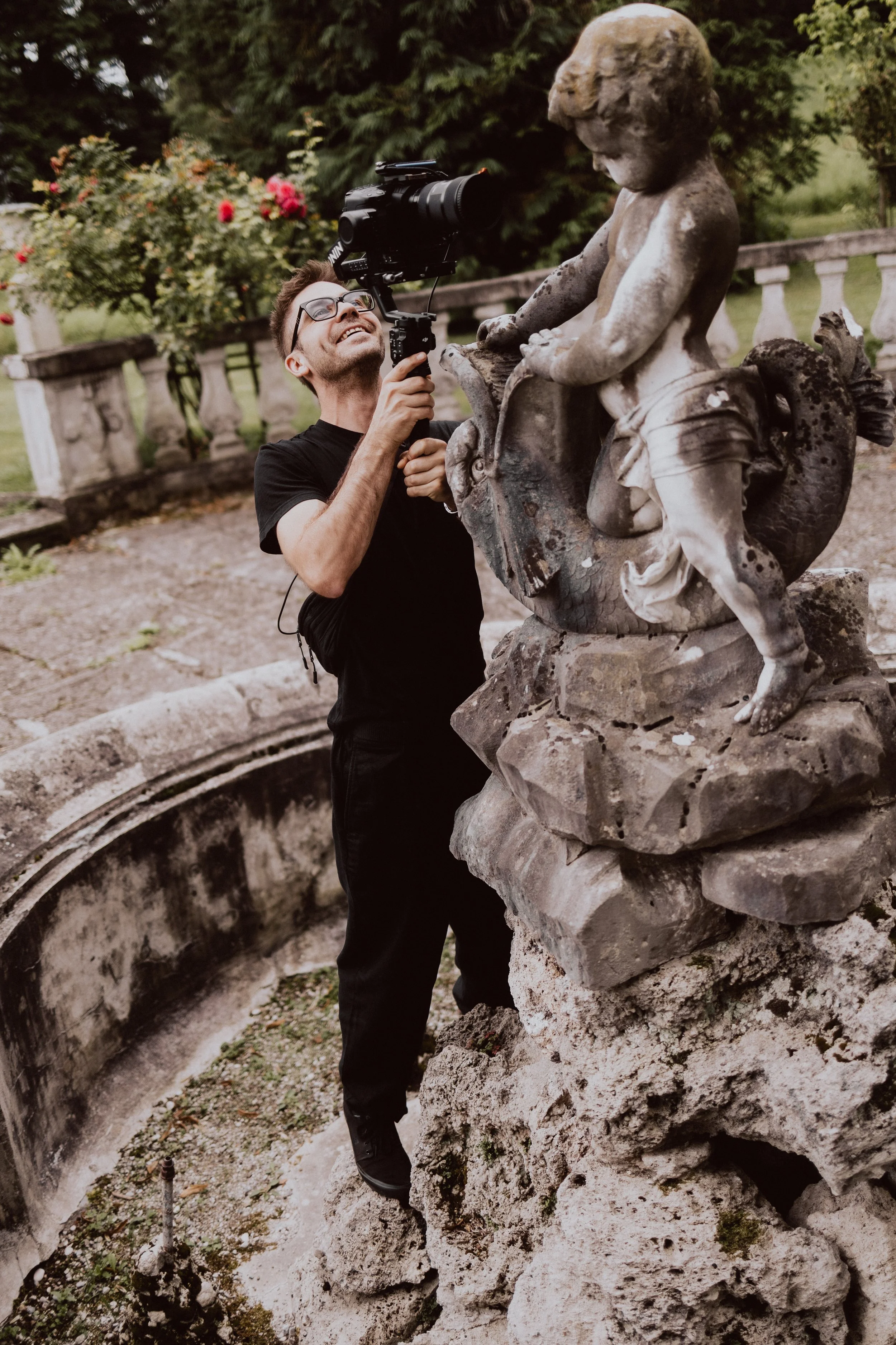 Professioneller Hochzeitsvideograf bei der Arbeit an einer Fontäne für einen dynamischen Hochzeitsclip in Bayern.