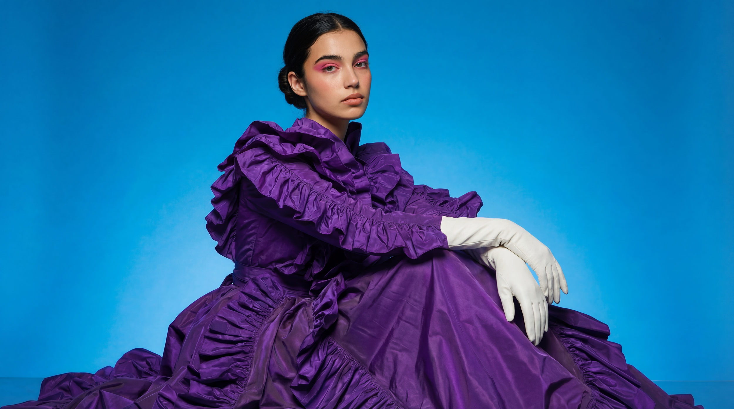 Notre approche – Femme robe violette manches bouffantes et gants blancs sur fond bleu, image IA et direction artistique par Ramisphere
