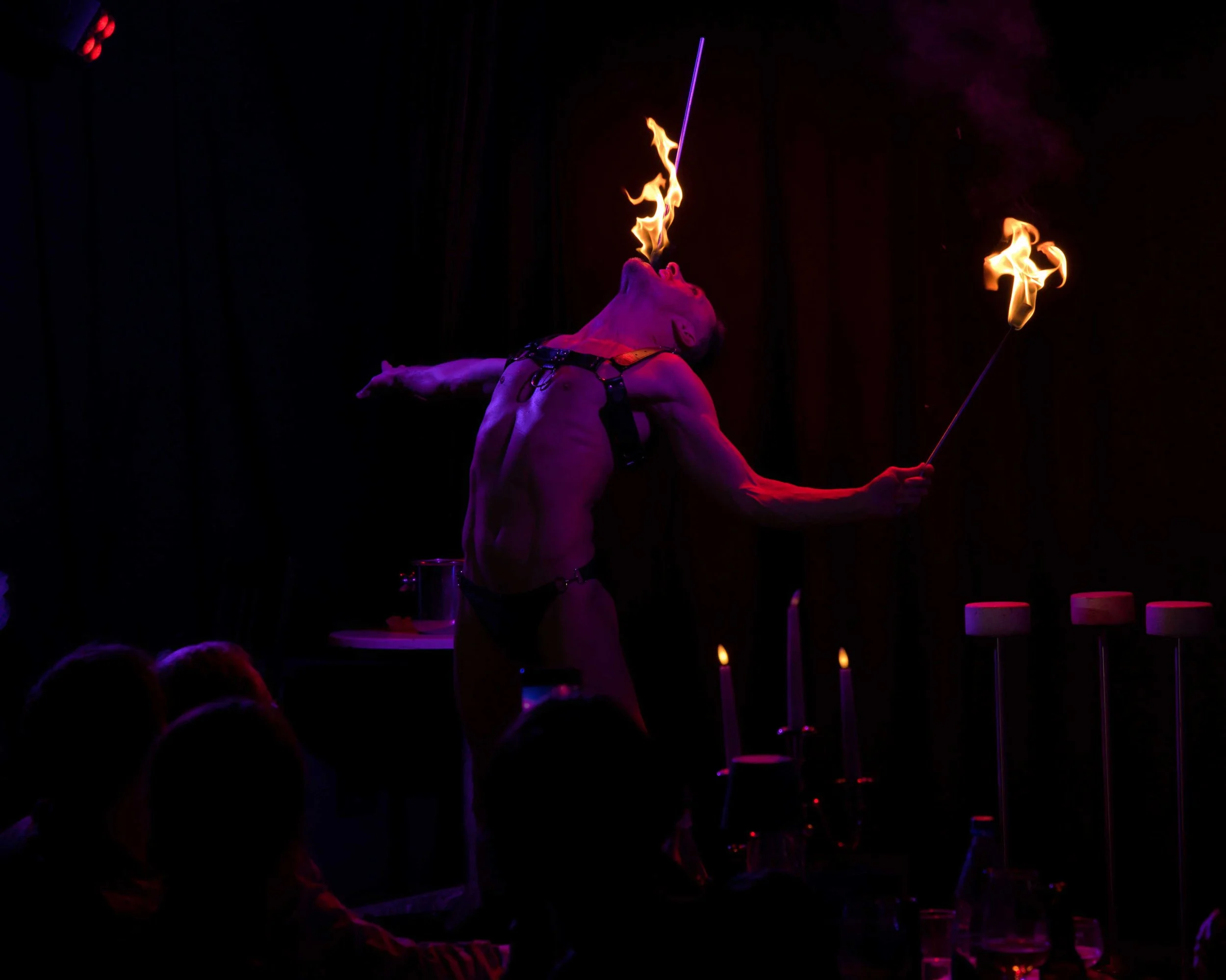 Ein akrobatischer Feuerkünstler bei einer Show, der Flammen aus seinem Mund und mit Fackeln hält.