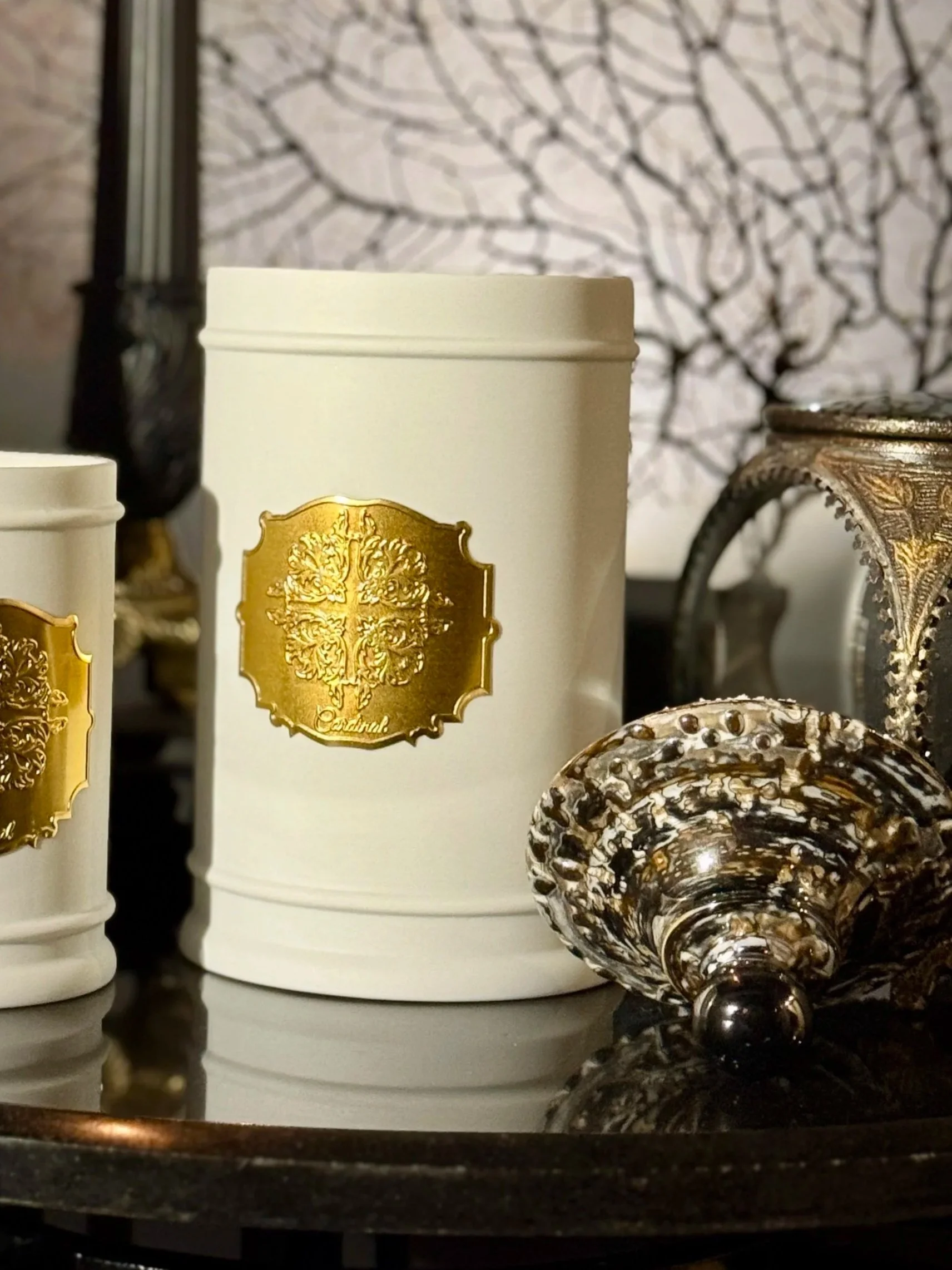 Différents contenants en céramique et un verre à gougé décoré avec un fond de motif d’arbres