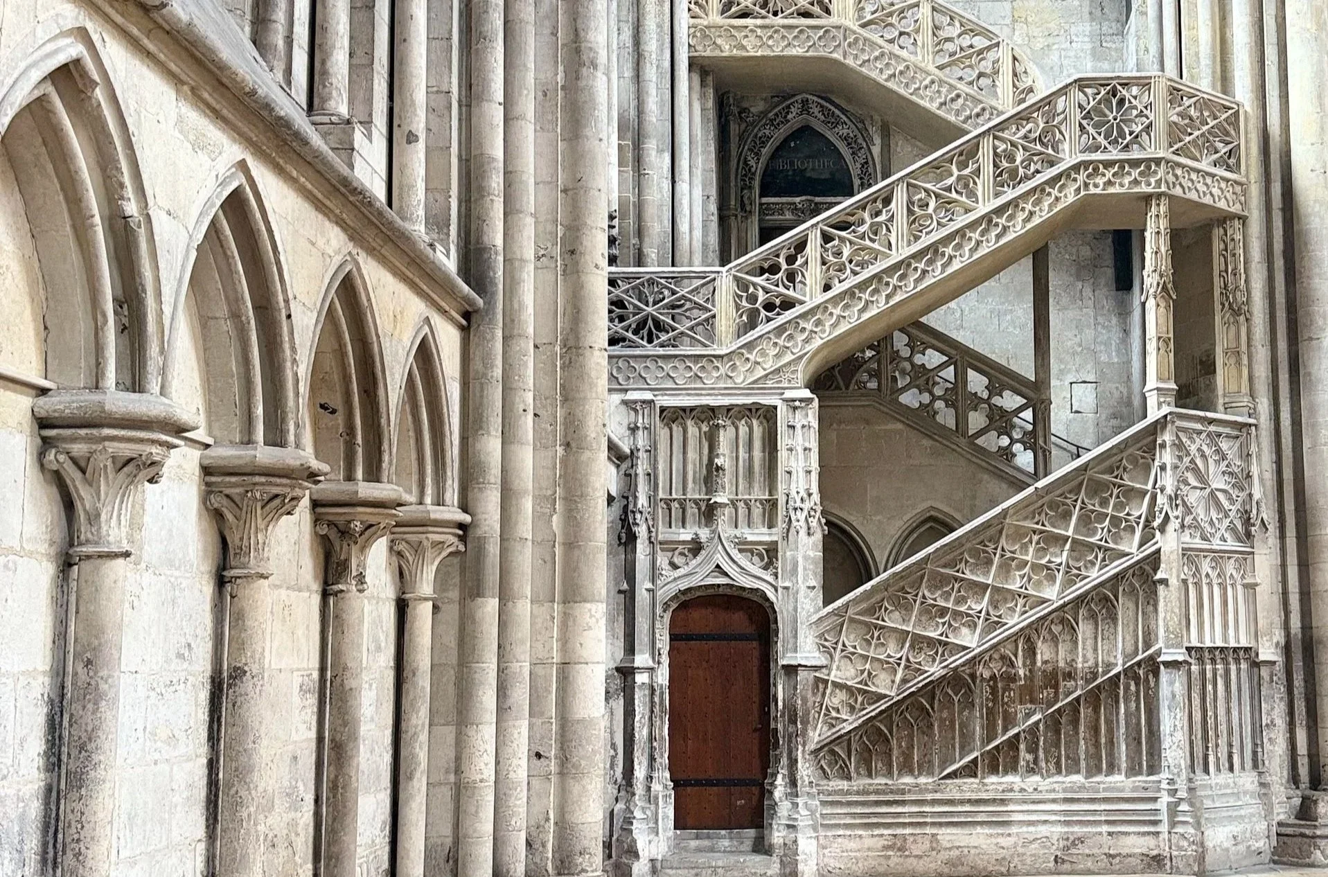 Escalier en pierre à l'intérieur d'une vieille cathédrale gothique avec des détails sculptés d'ornements en pierre et des arches.