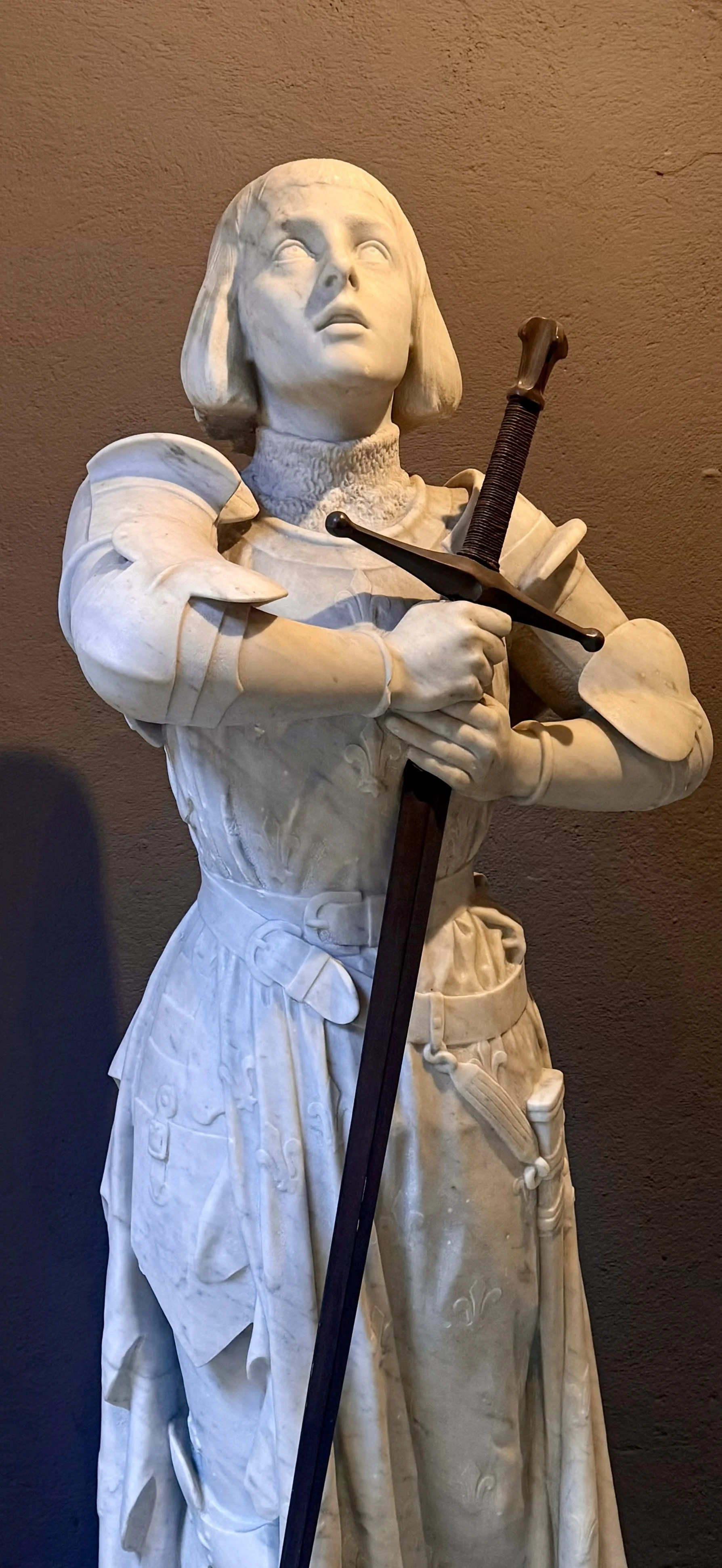 Statue en marbre d'une femme en costume médiéval, tenant une épée.