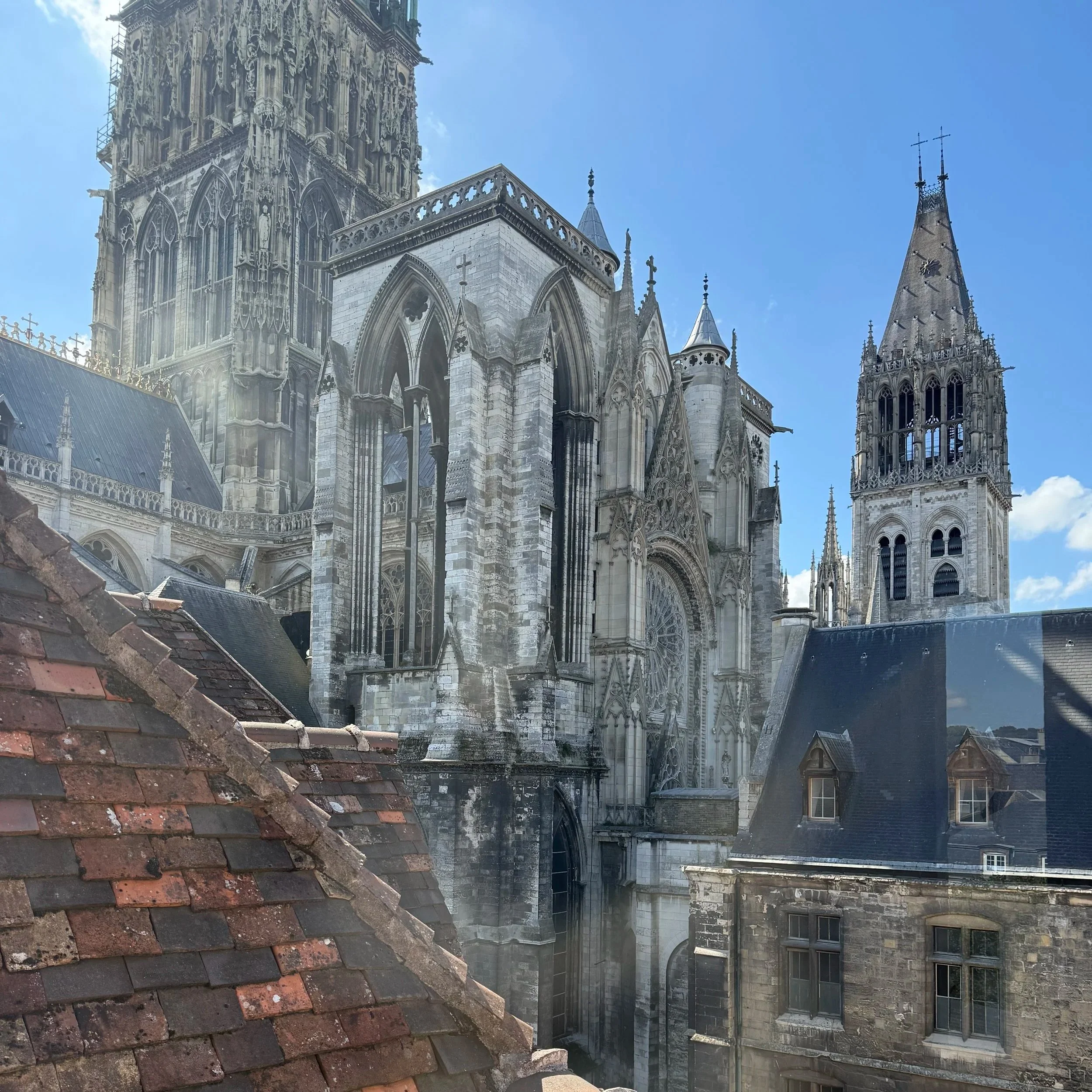 Une vue du haut de cathédrale gothique avec des tours pointues et des détails architecturaux ornés contre un ciel bleu.