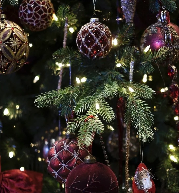 Boules de Noël rouges et dorées suspendues sur un sapin décoré de lumières