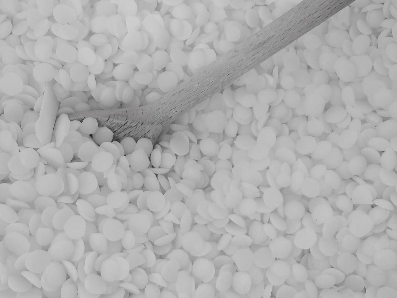 Un mélange de petites billes rondes blanches avec une cuillère en bois dans le mélange.