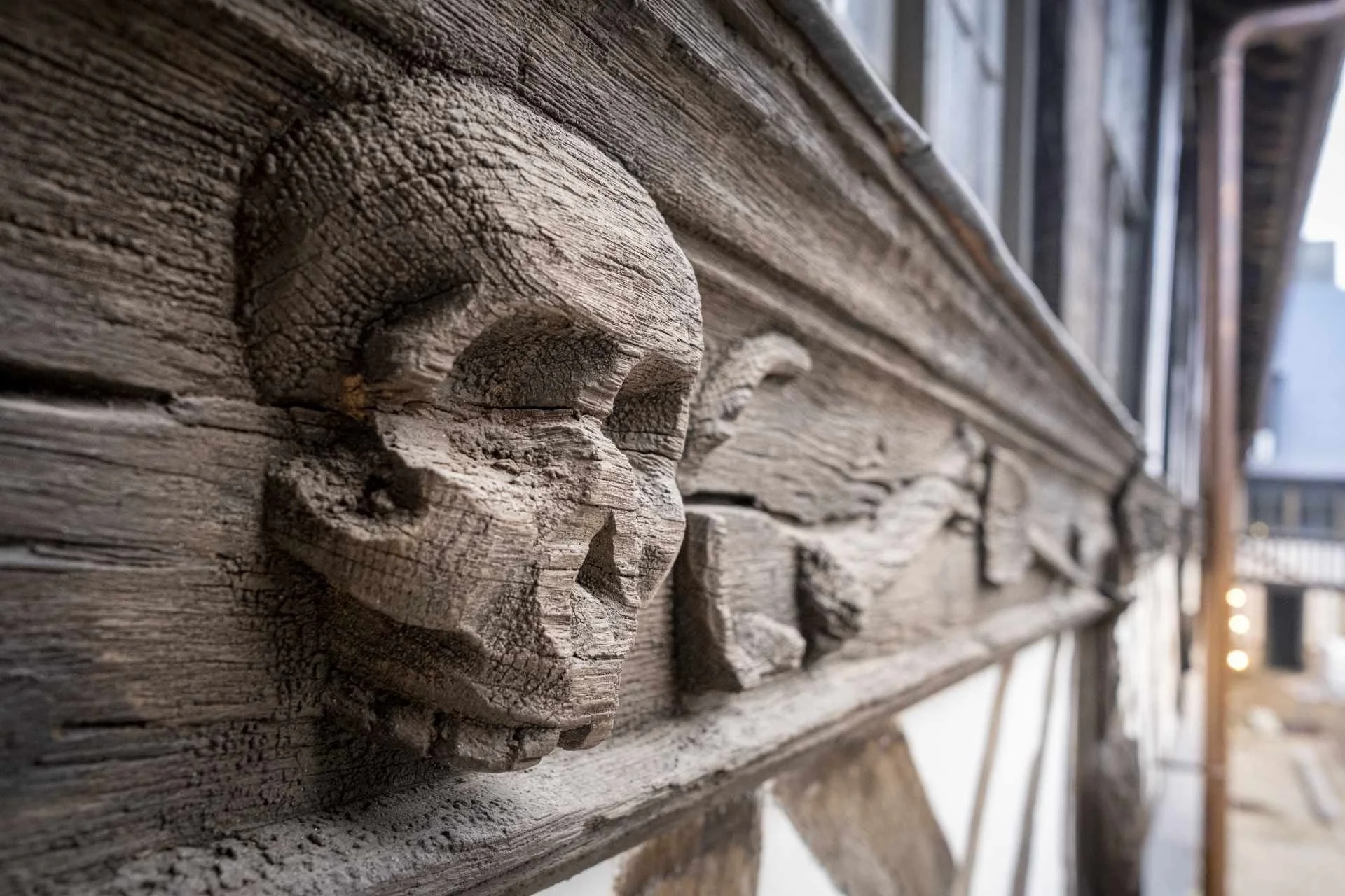 Vue en gros plan d'une façade en bois usé avec des détails de texture, notamment des nœuds et des fissures.