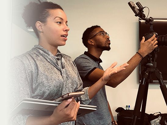 Two people working with camera equipment in a studio or office setting