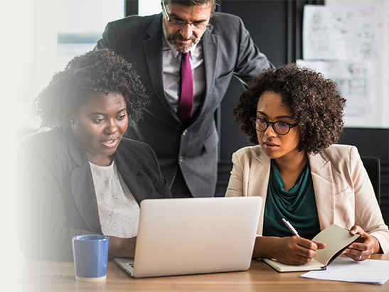 Three professionals collaborating around a laptop in a modern office.