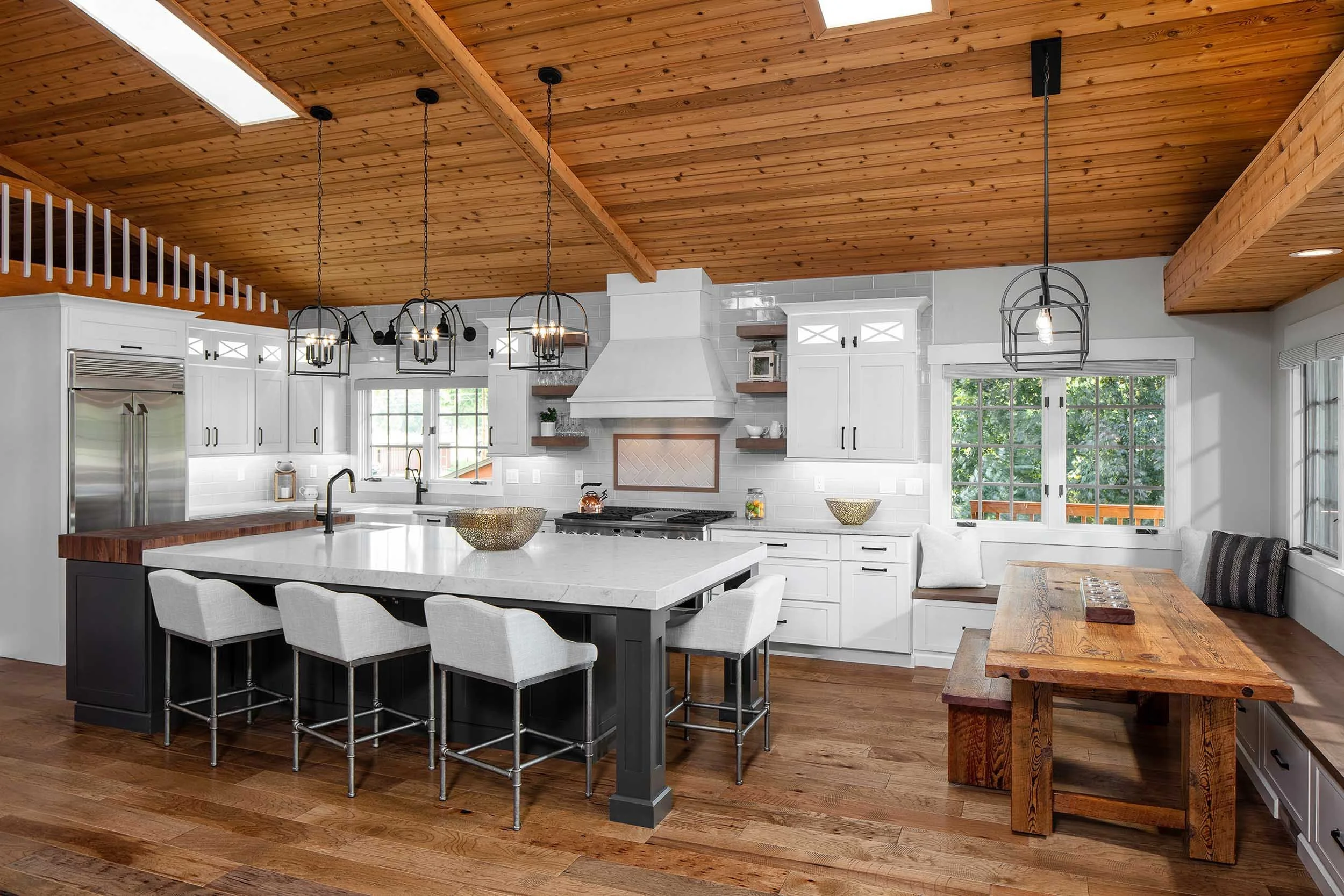 Modern kitchen with white cabinets, black and wood accents, and a wooden ceiling with pendant lighting.