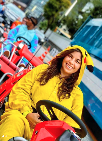 Person in Pikachu onesie driving a go-kart on a street.