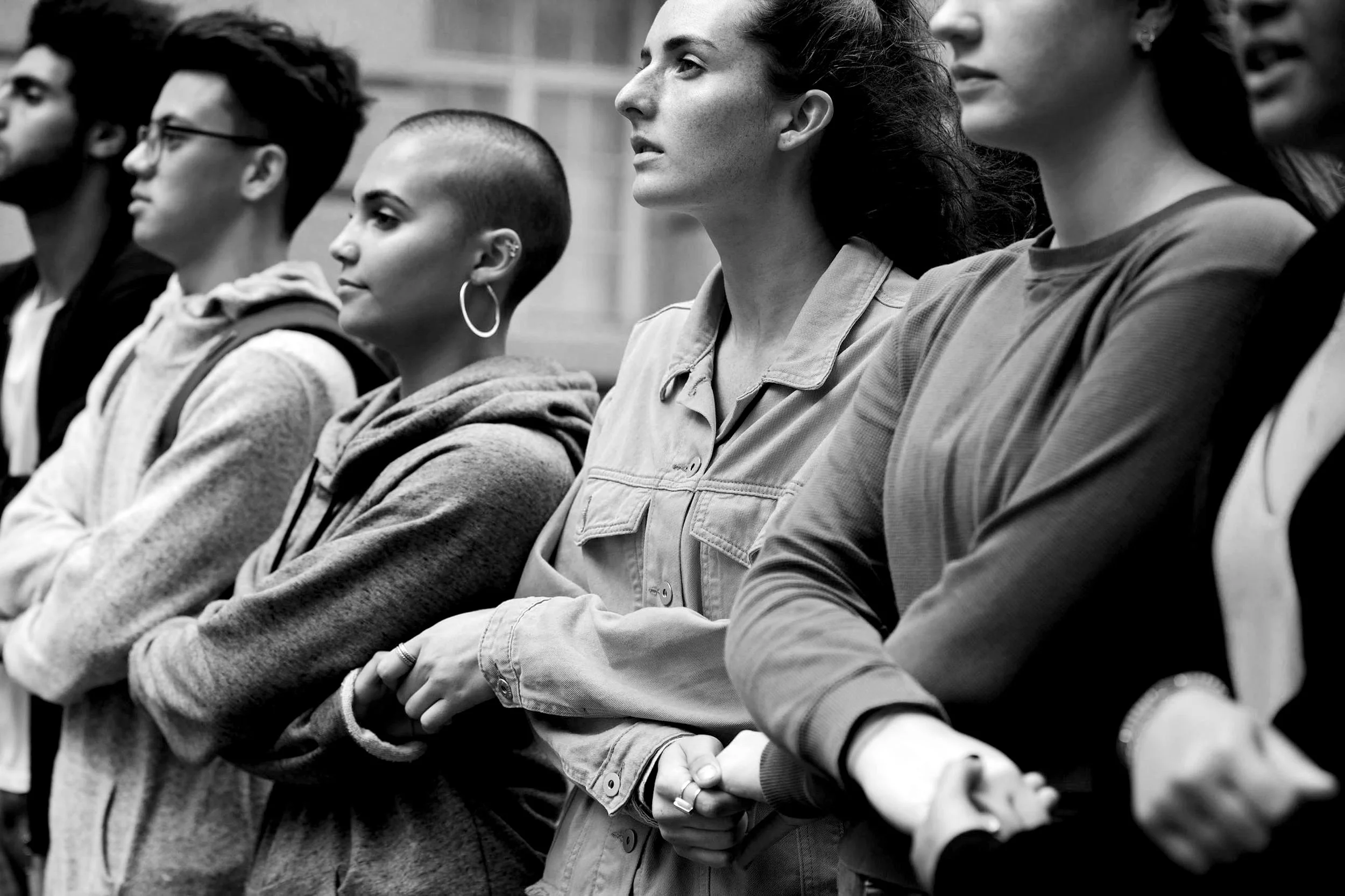 Eine Gruppe von Menschen, die im Sitzen zuhören, in einem Schwarz-Weiß-Foto. Sie zeigen unterschiedliche ethnische Hintergründe und tragen verschiedene Kleidung.