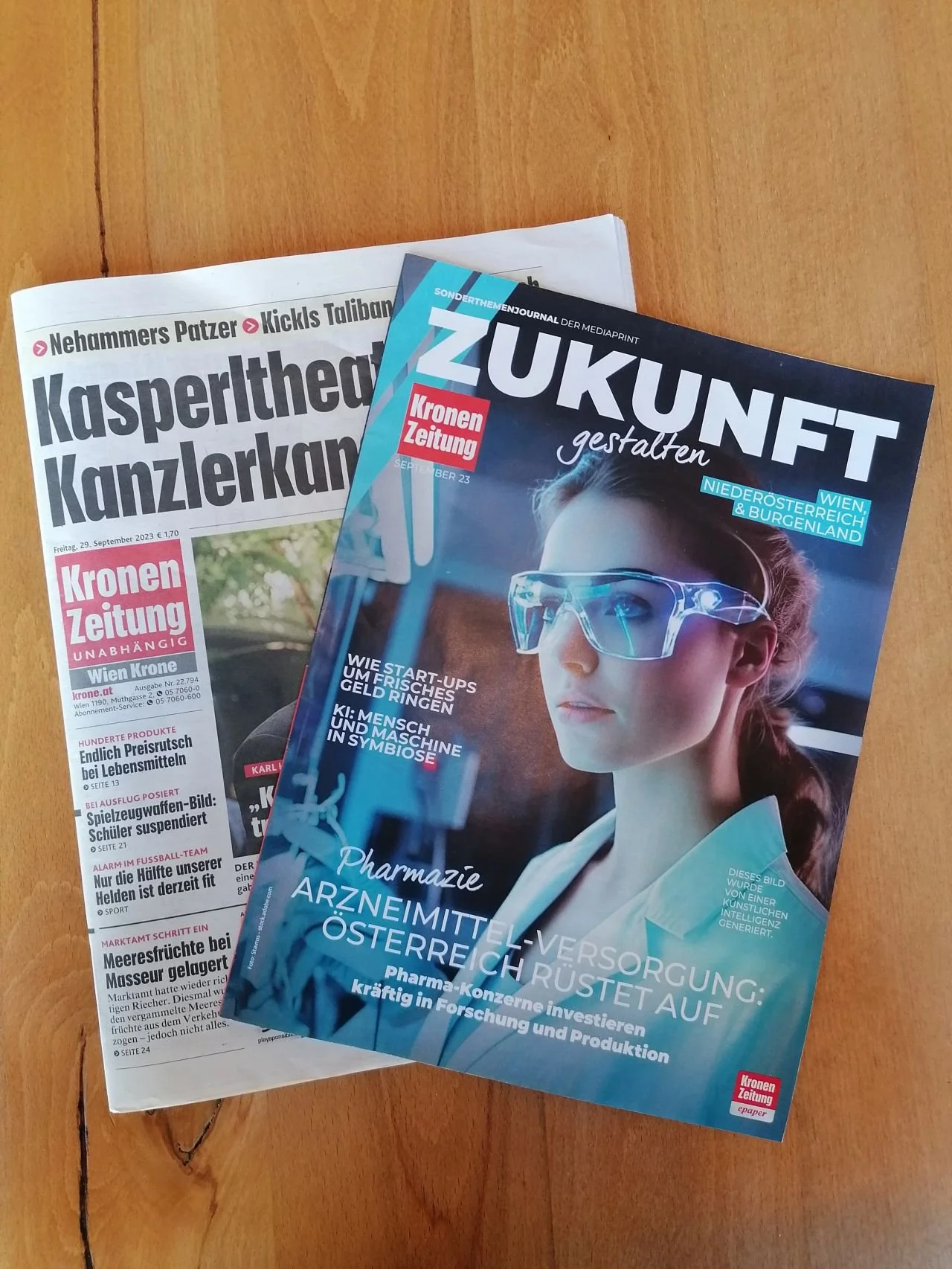 Zeitschrift 'Zukunt gestalten' mit einem jungen Wissenschaftlerinnen im Labor auf dem Cover, darunter eine Zeitung 'Kronen Zeitung'.