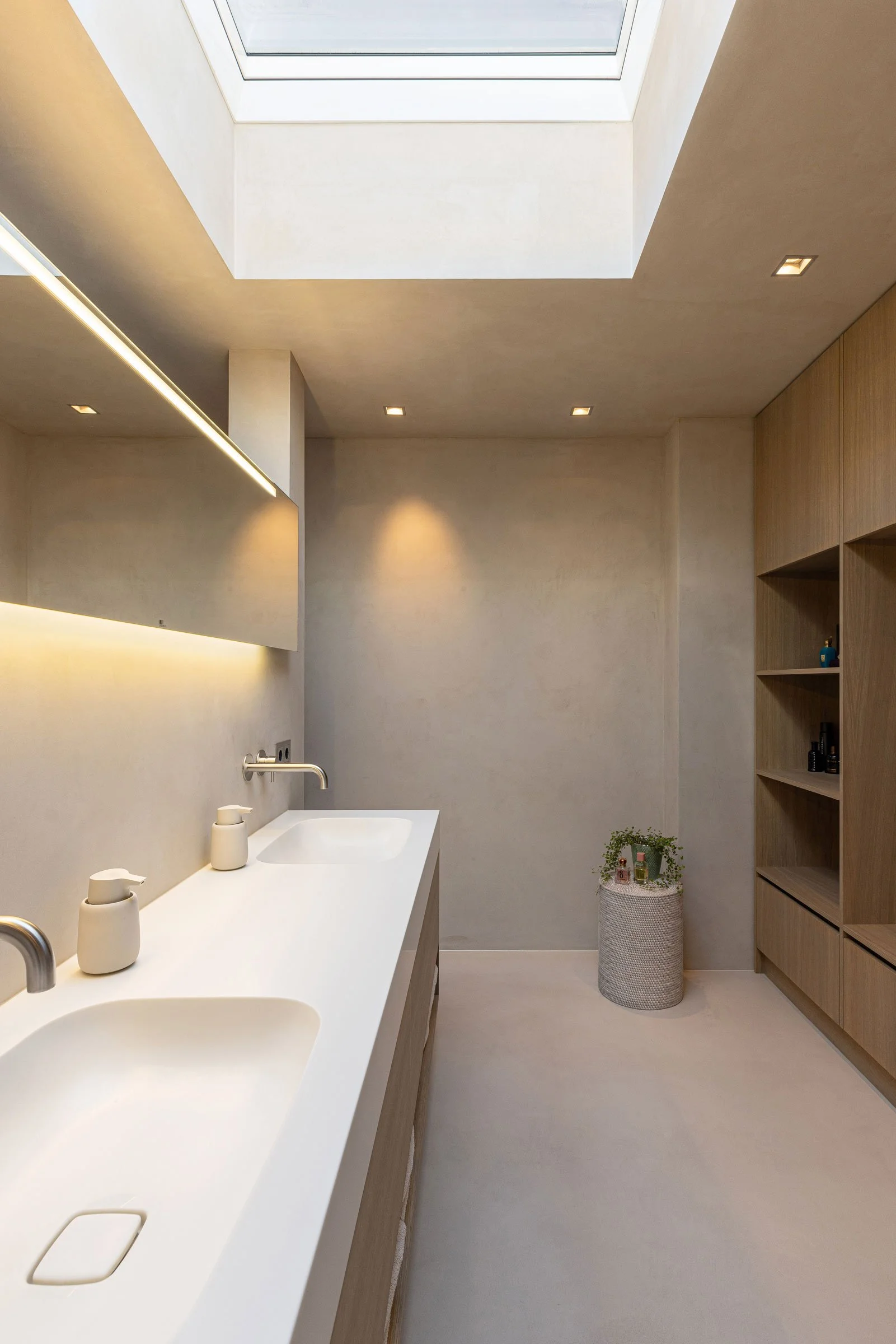 Ein modernes Badezimmer mit Doppelwaschbecken, Holzregalen und einem Glasdach für natürliches Licht.