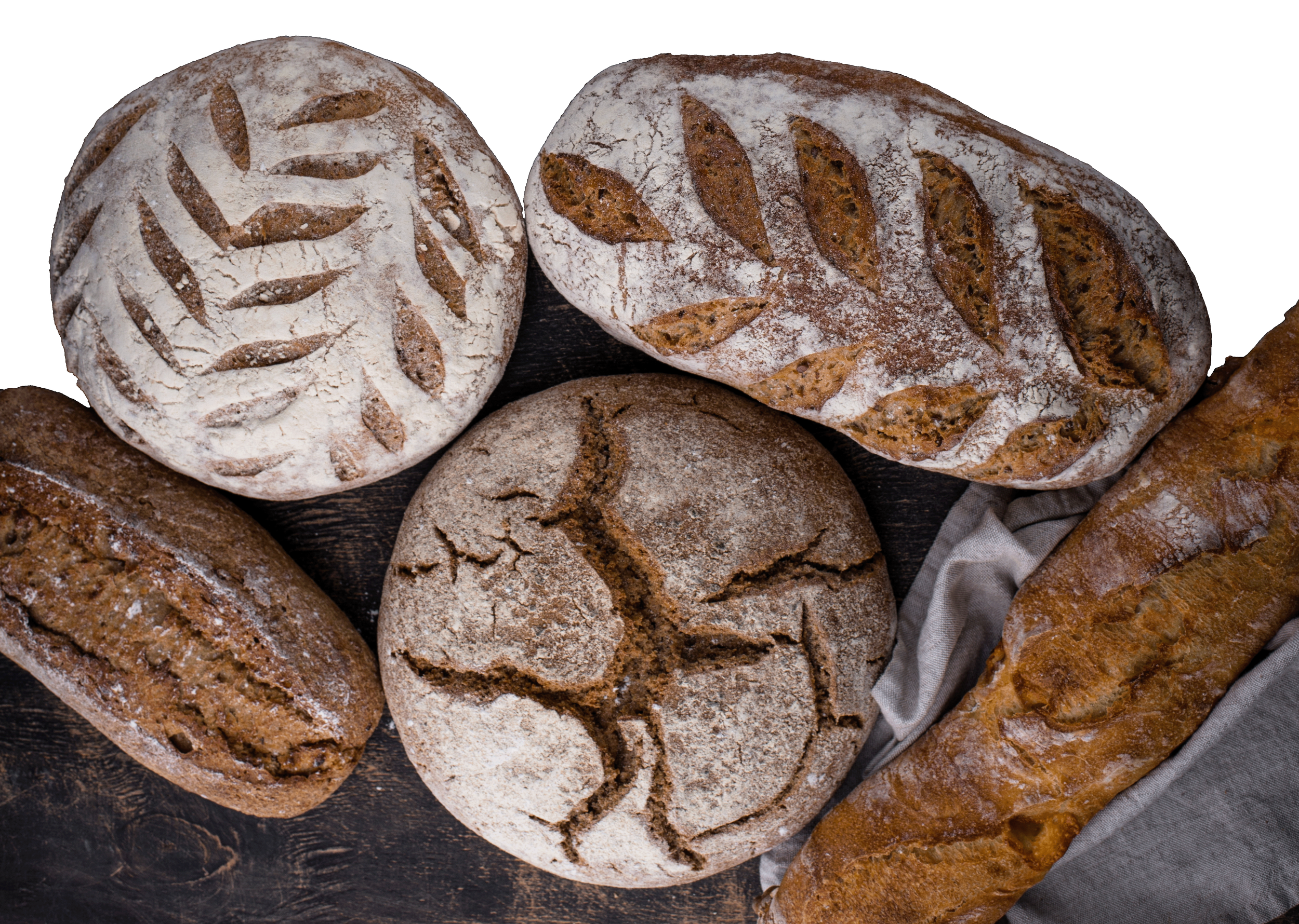 Assorted loaves of bread with different shapes, textures, and scoring patterns, resting on a dark wooden surface with a cloth.