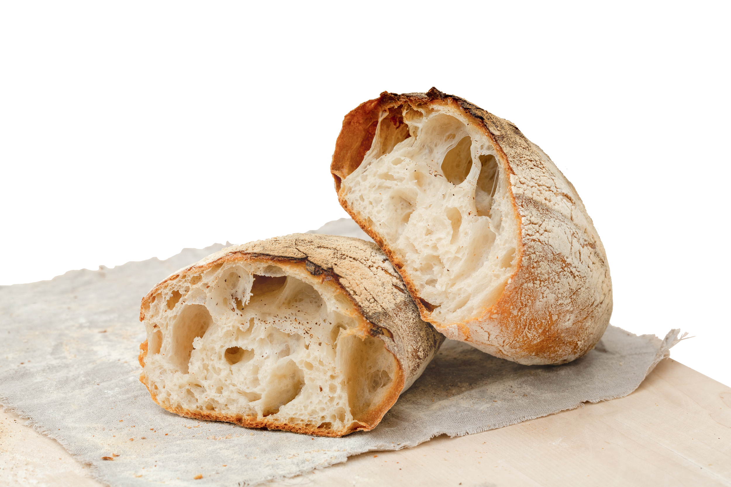 Sliced loaf of rustic bread with a crusty exterior and airy, irregular crumb on a light-colored cloth.