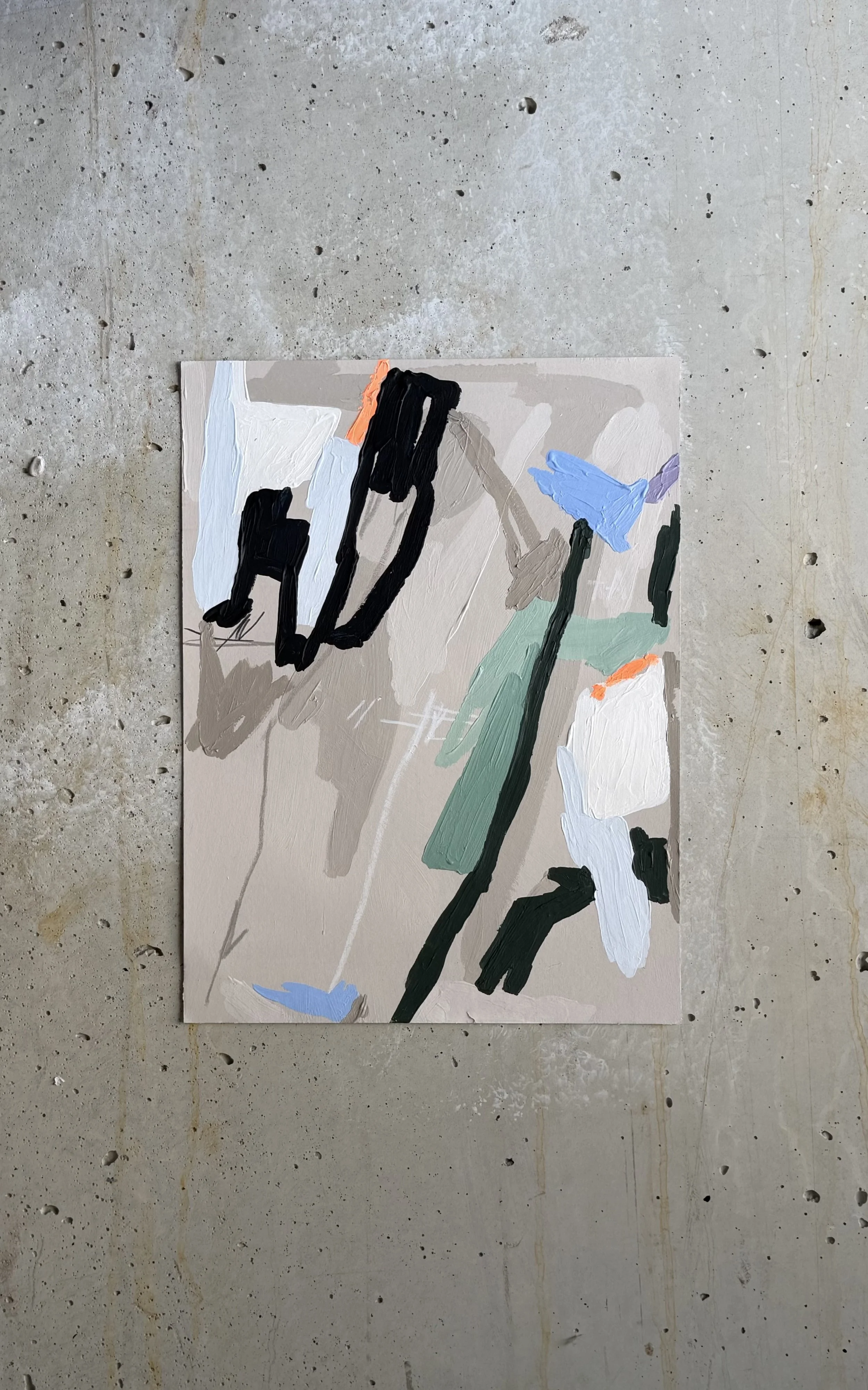 An abstract painting with bold, expressive brushstrokes in black, white, blue, green, and orange on a beige background, placed on a concrete floor by Aura Delamotte