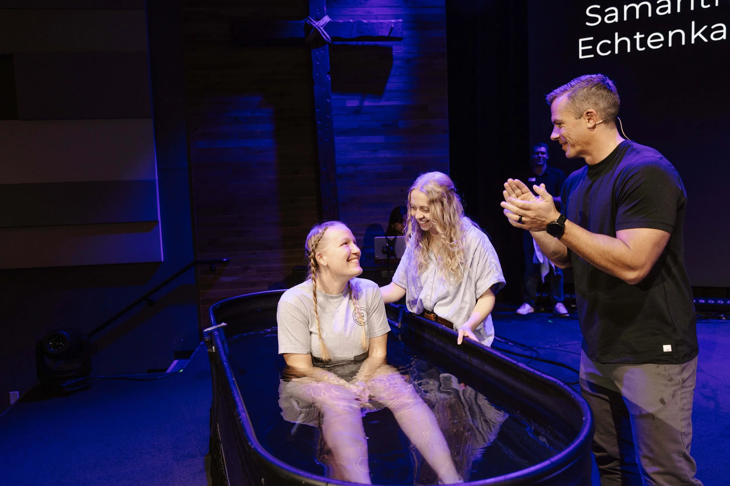 A young woman baptizing another.