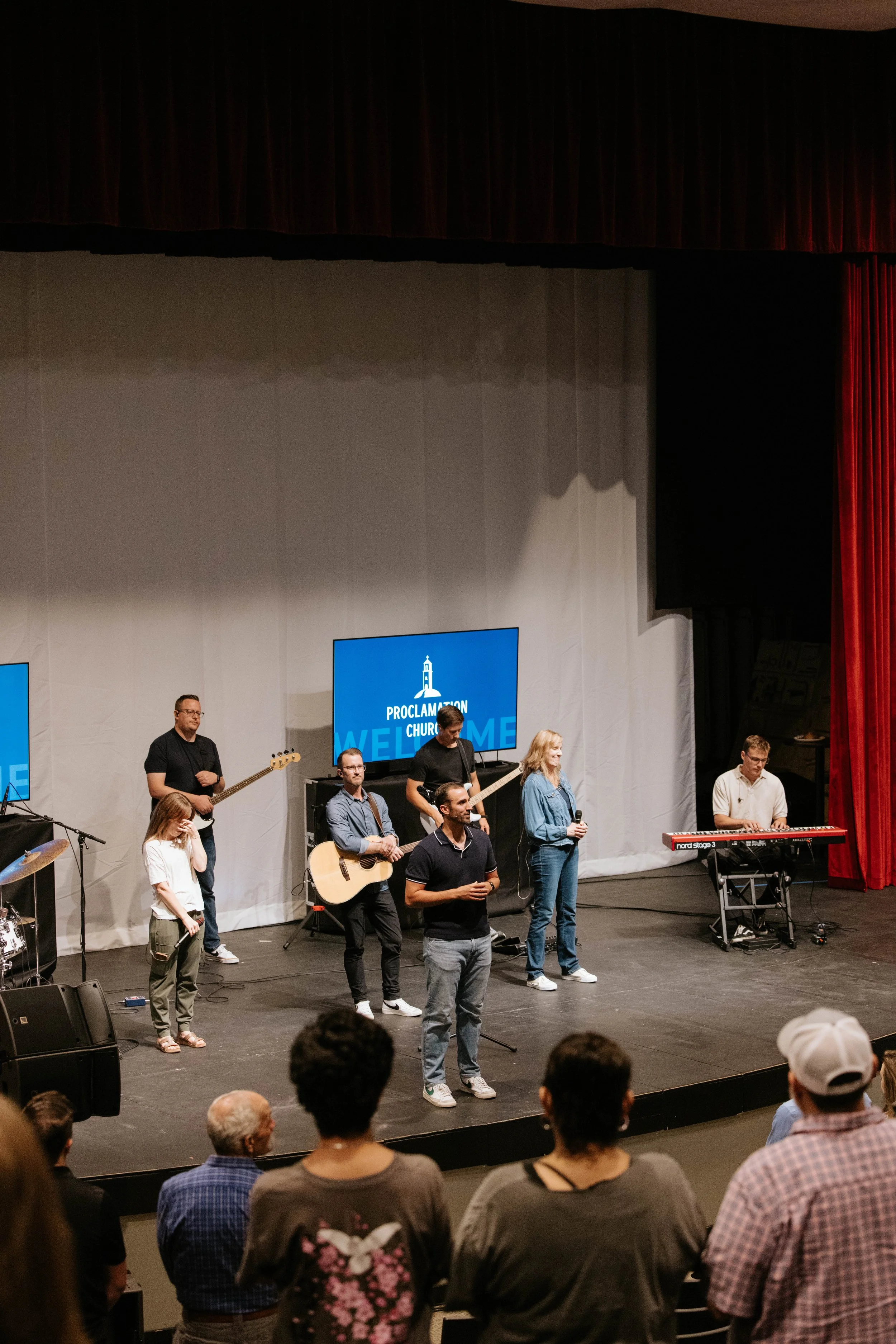 A church service with a band performing on stage in front of an audience.