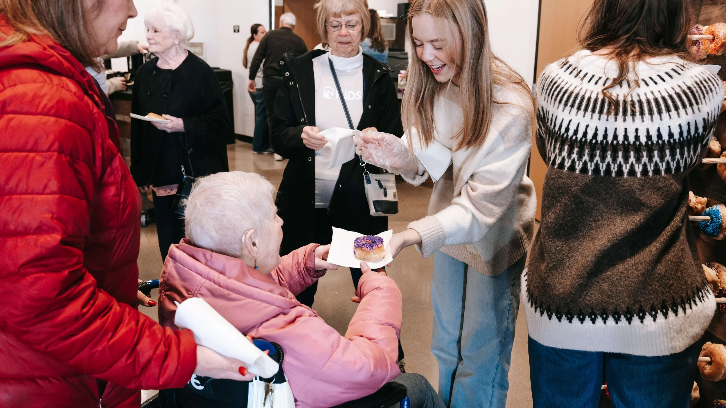A volunteer at Storyline Church giving an elderly woman a donut.