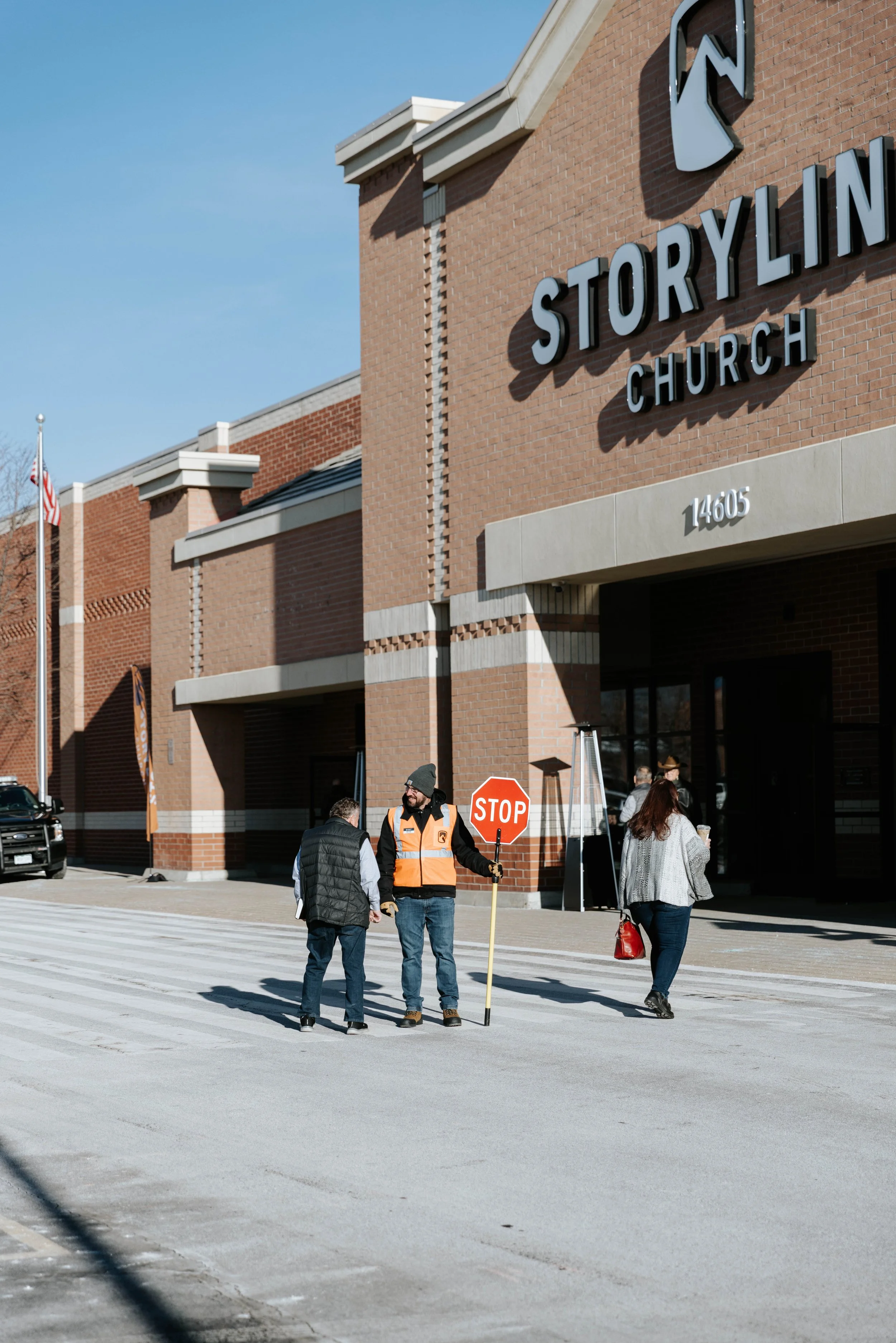 A woman reading a book at a microphone on a stage during a performance, with children around her, decorated with lights and greenery.