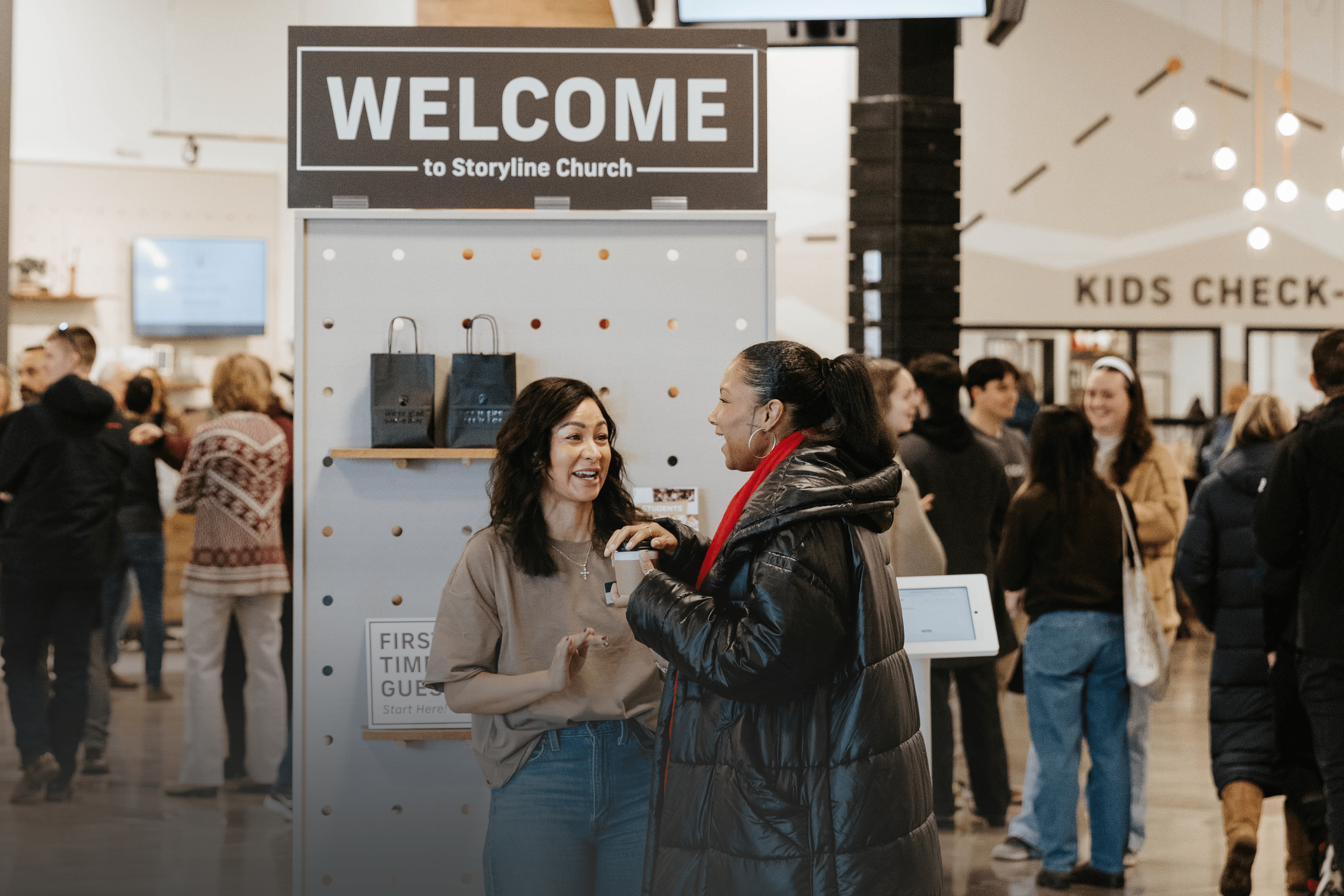 A welcoming volunteer smiling in the lobby of Storyline Church.