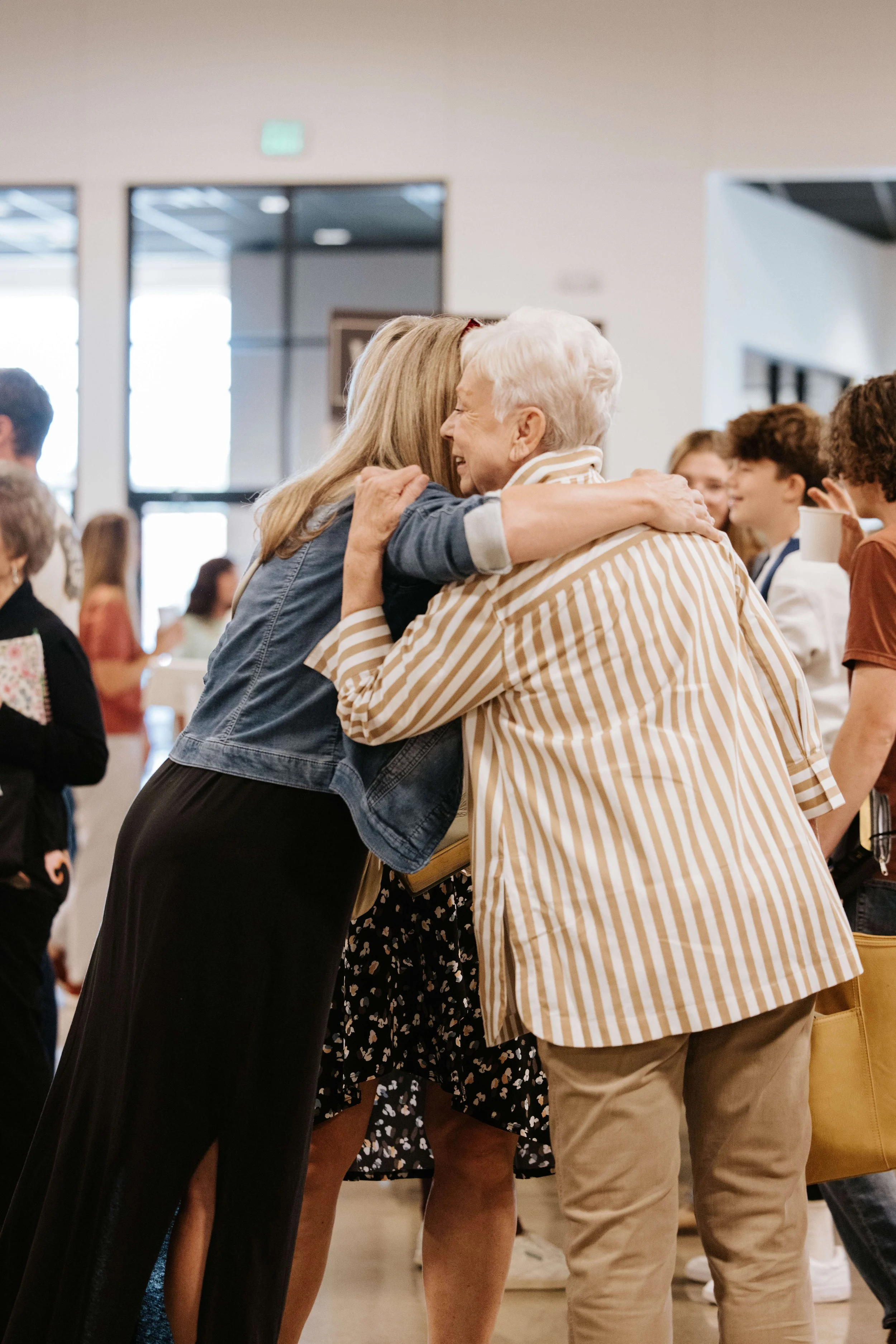 Two women embracing warmly at what appears to be a social gathering or event.