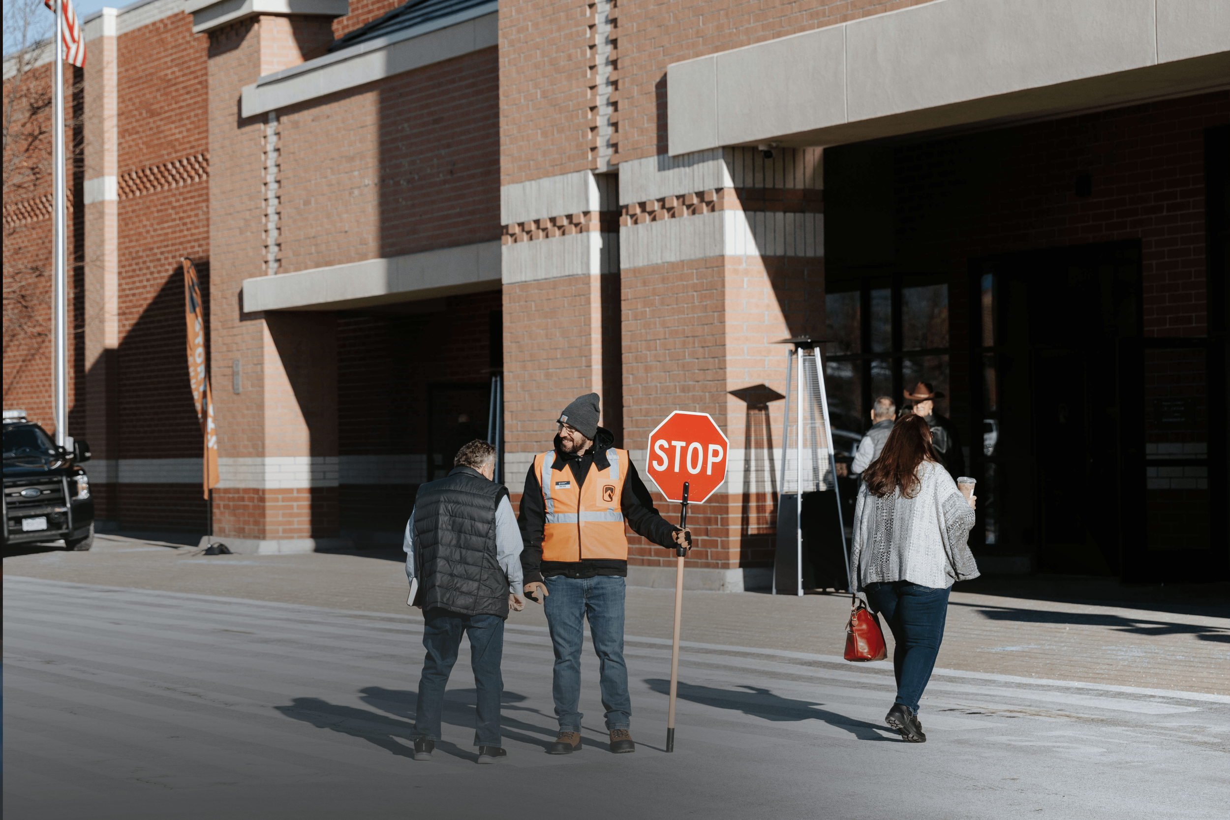 A group of people at a tented outdoor setup, with one person handing out food and others holding boxes in an urban area.