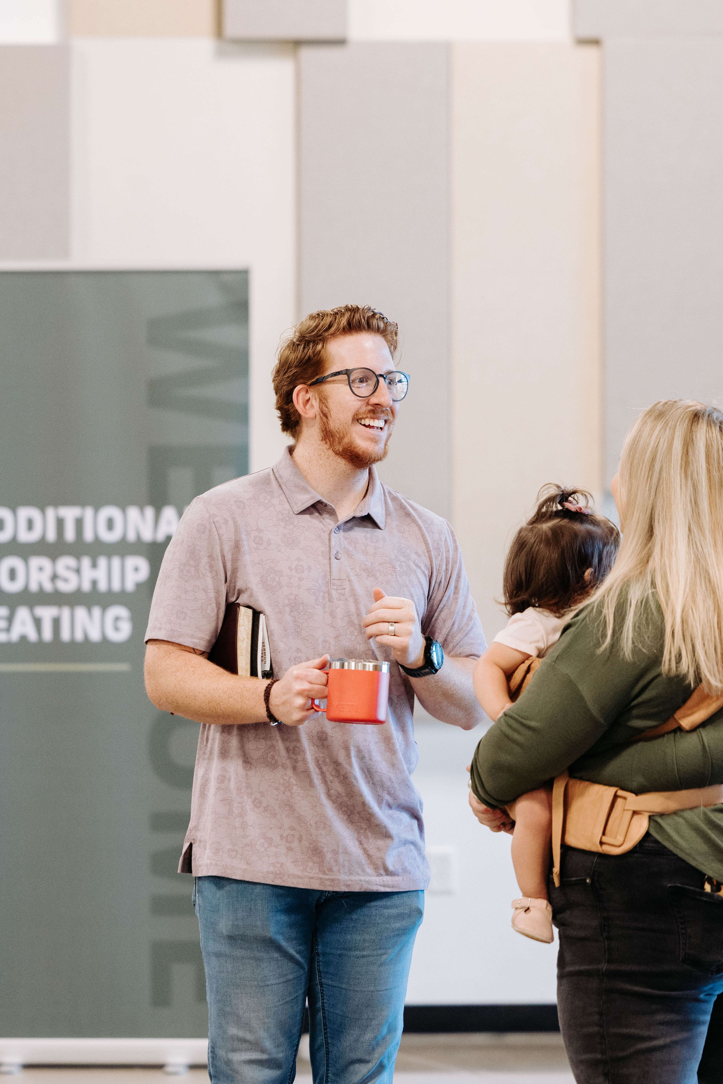 A man welcoming people to the church in the lobby. 