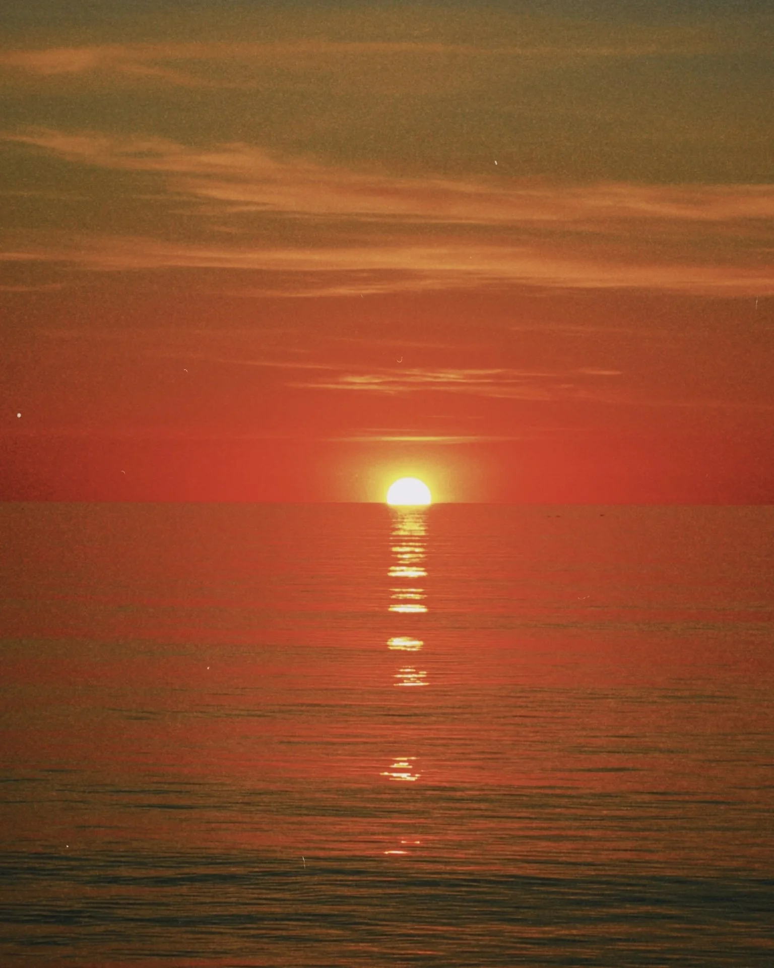 Sun setting over calm water with clouds and a few stars visible in the sky. Photo taken on the island of Læsø, part of the Aarhus Region.