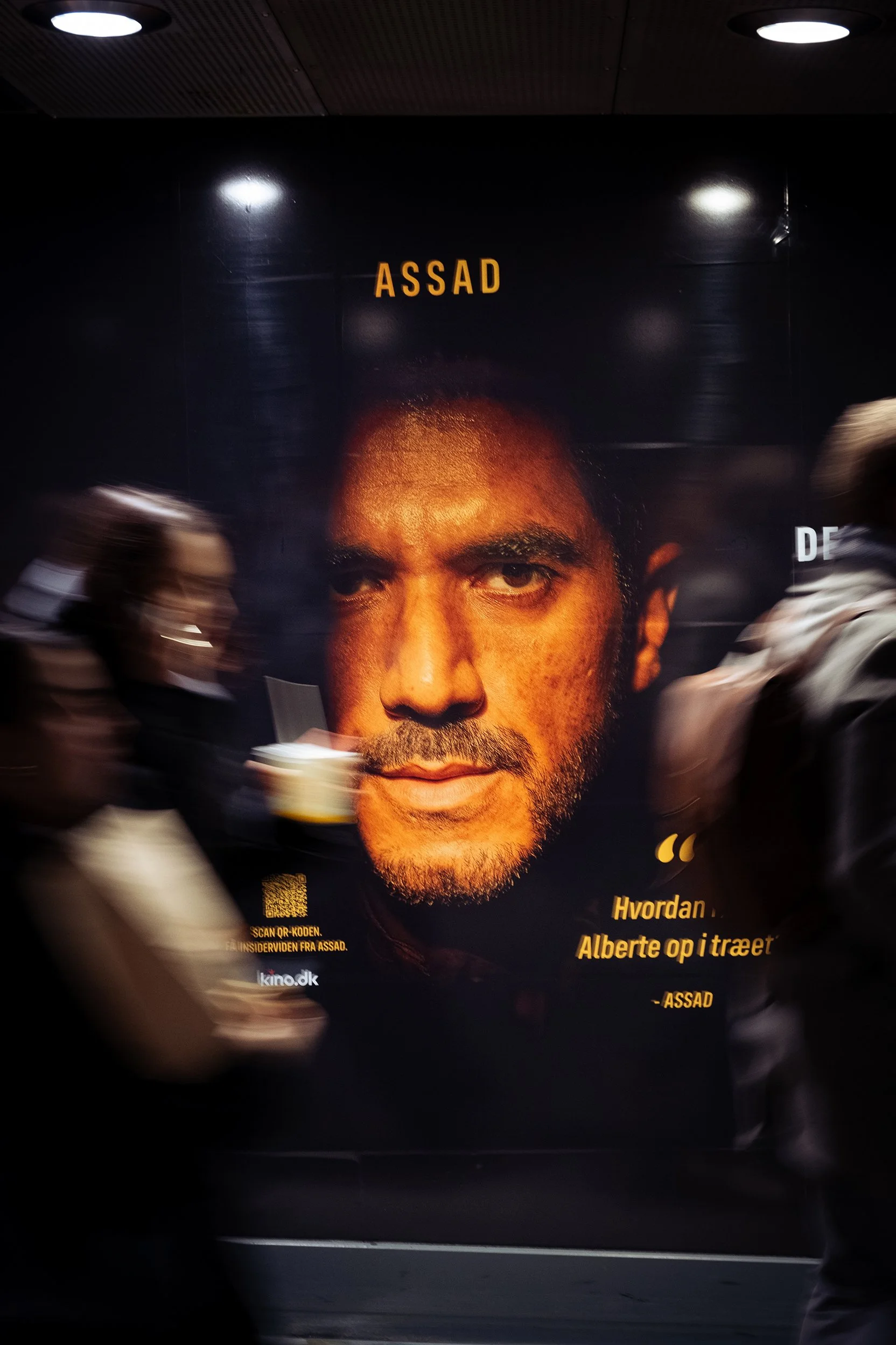 Plakat med et portræt af en mand med mørkt hår og skæg, teksten 'ASSAD' øverst, og yderligere tekst nederst: 'Hvordan Albert op i træet'.