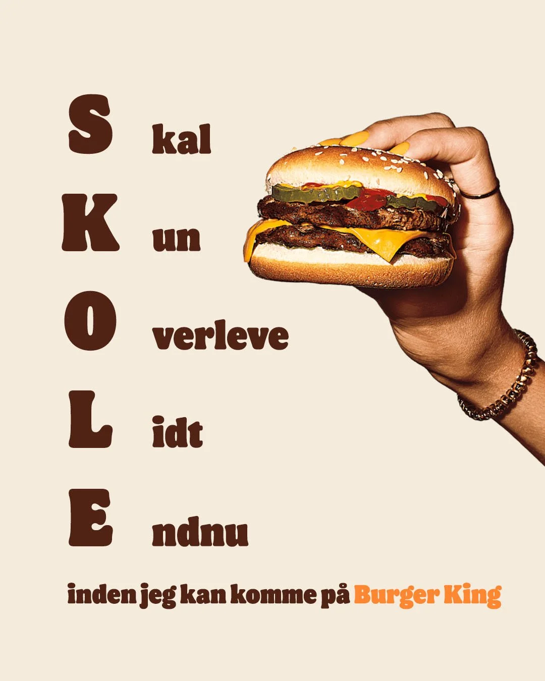 En person holder en stor burgermed ost, selleri, pickles, og en bøf. Tekst på billedet siger 'S kal kun overleve lidt før jeg kan komme på Burger King'.
