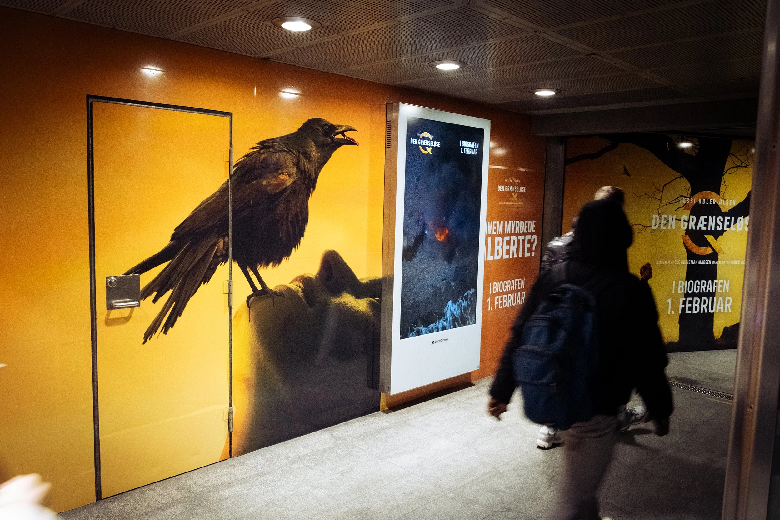 Kunstværk med en stor fugl, der sidder på en persons ansigt, på en gul baggrund. Der er tekst på væggen om en film, der vender tilbage i biograferne den 1. februar.