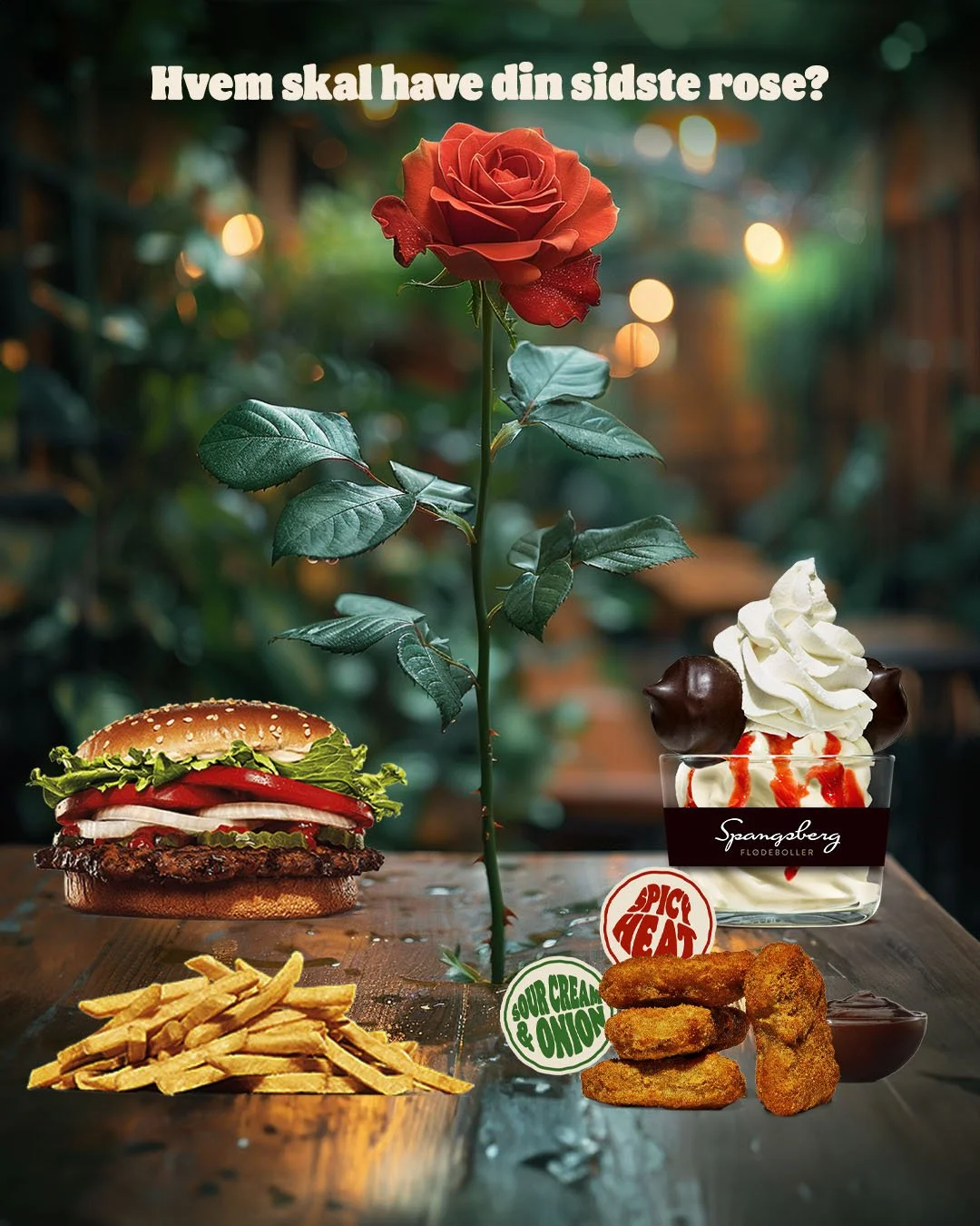 En blomstrende rød rose midt på et bord, omgivet af forskellige madvarer: en cheeseburger, en skål med skumfiduser og chokoladesovs, pommes frites, chicken nuggets, og en skål med is og chokoladekugler. Tekst på billedet spørger, 'Hvem skal have din 