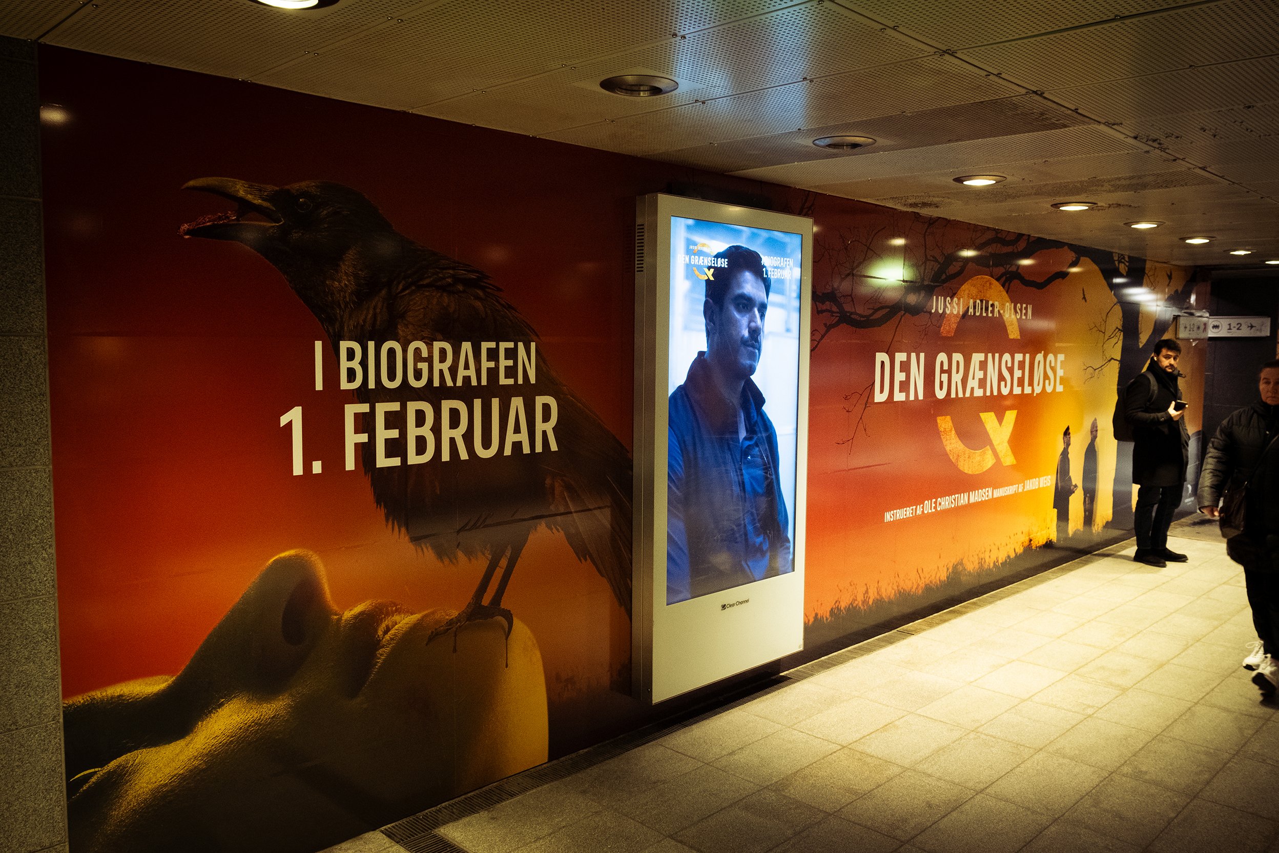 Plakat for filmen 'Den Grænseøse' med ugle og menneskelig profil, tekst om premieren den 1. februar, afrundet med tre mennesker i undergrundsstation.