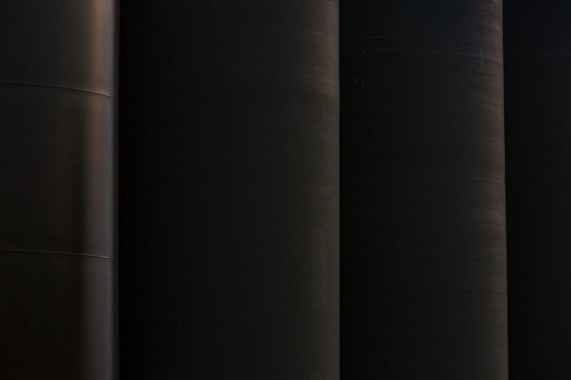 Close-up image of multiple dark-colored, cylindrical objects with smooth surfaces and subtle horizontal textures.