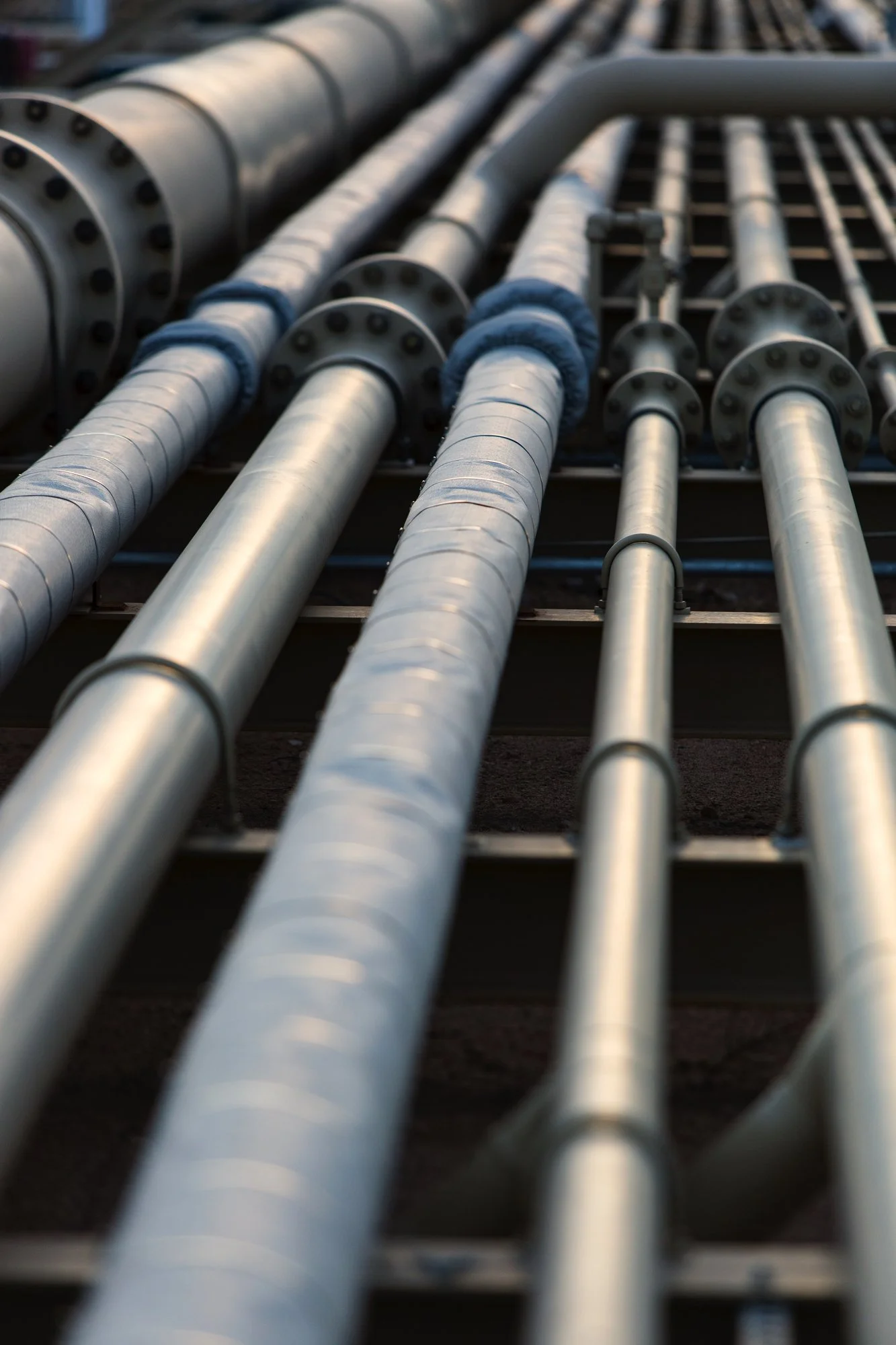 Multiple metal pipes and flanges installed on a structural framework.